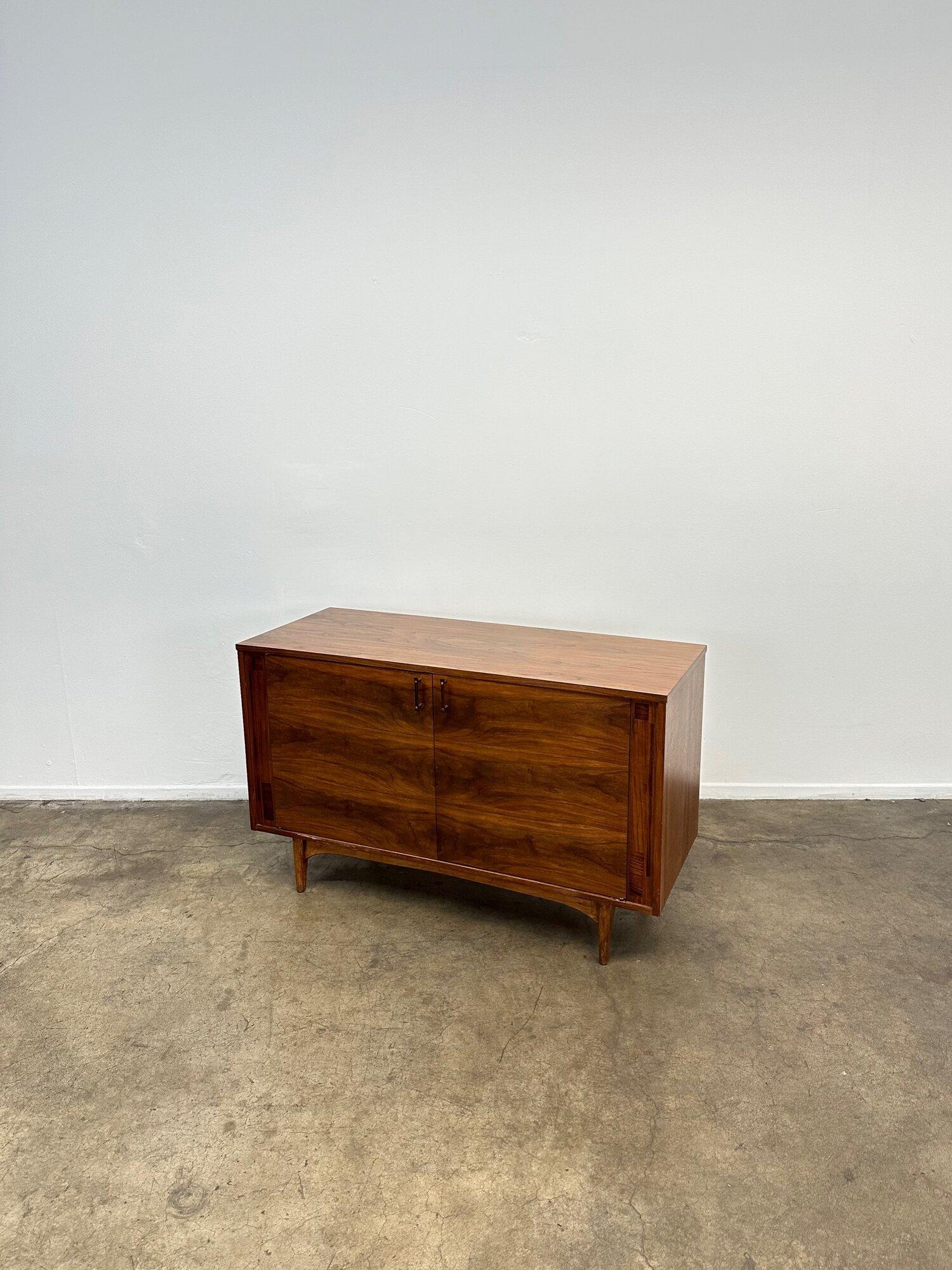 Fully restored credenza made in walnut wood featuring rosewood handles with brass, two smooth sliding drawers with makers mark inside, contrasting veneer details, half shelf inside and all on tapered legs.
 