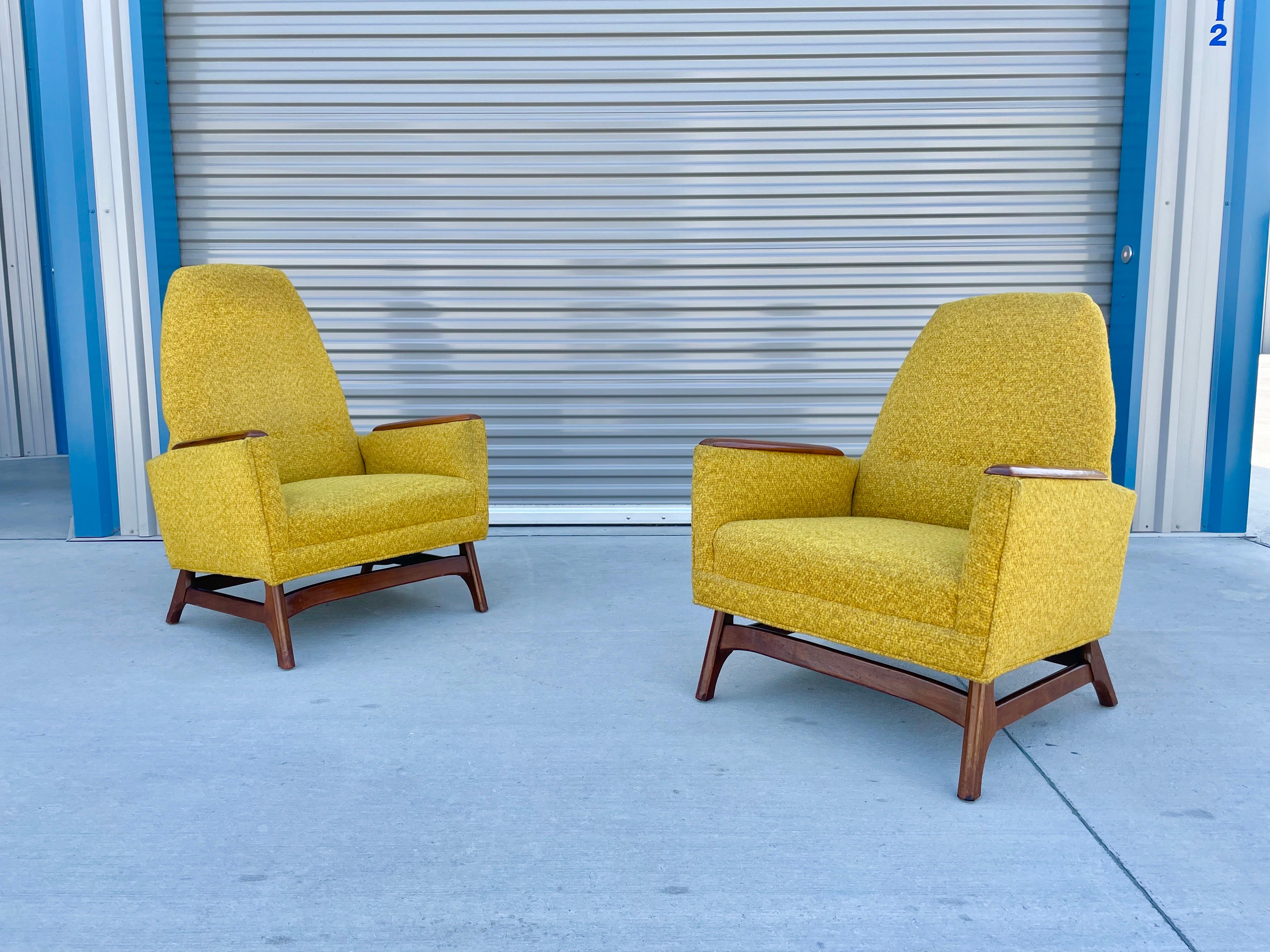 Midcentury walnut lounge chairs in the style of Adrian Pearsall. These chairs feature a vintage yellow upholstery with a sculpted solid walnut base and armrests. These chairs are price great for anyone who wants to reupholster them or use them as is.