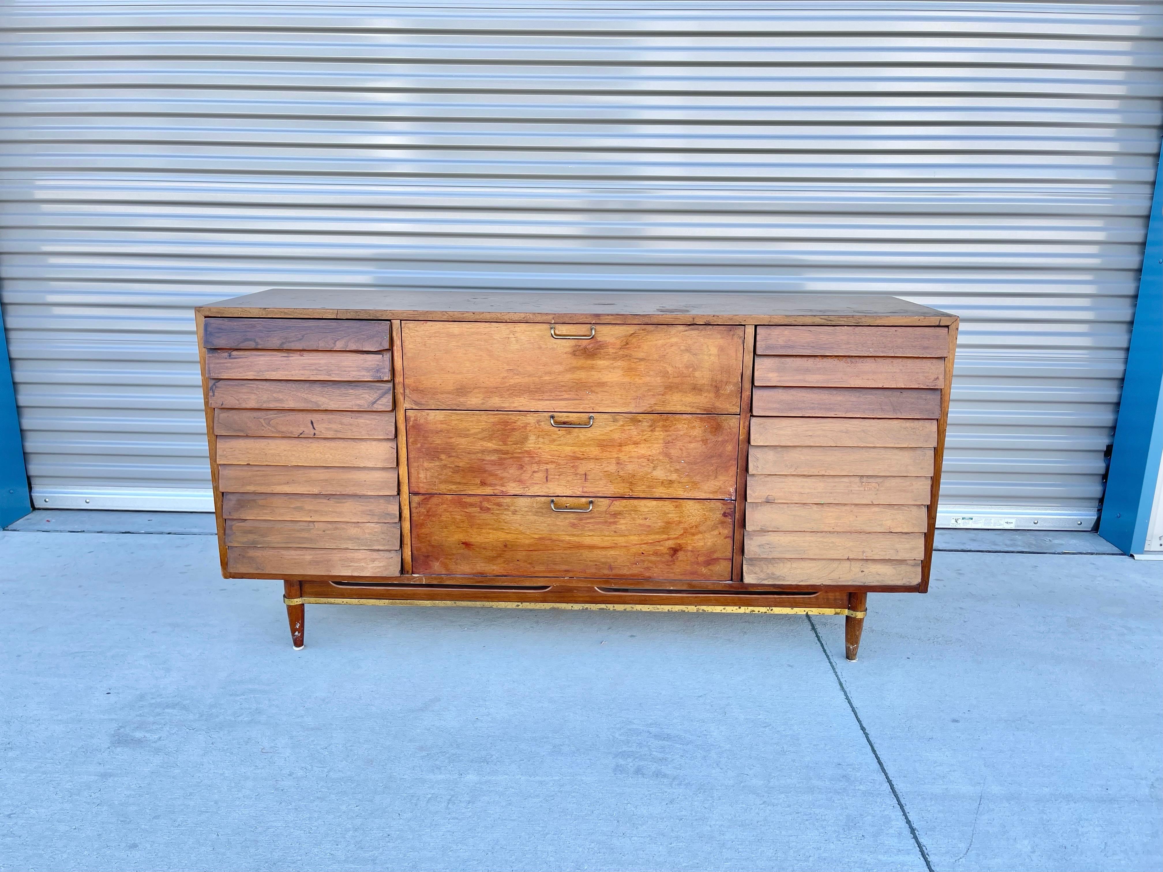 Mid-century walnut dresser designed and manufactured by American of Martinsville in the United States circa 1960s. This beautiful dresser features a walnut finish with nine pull-out drawers. The dresser also features a louvered front design giving