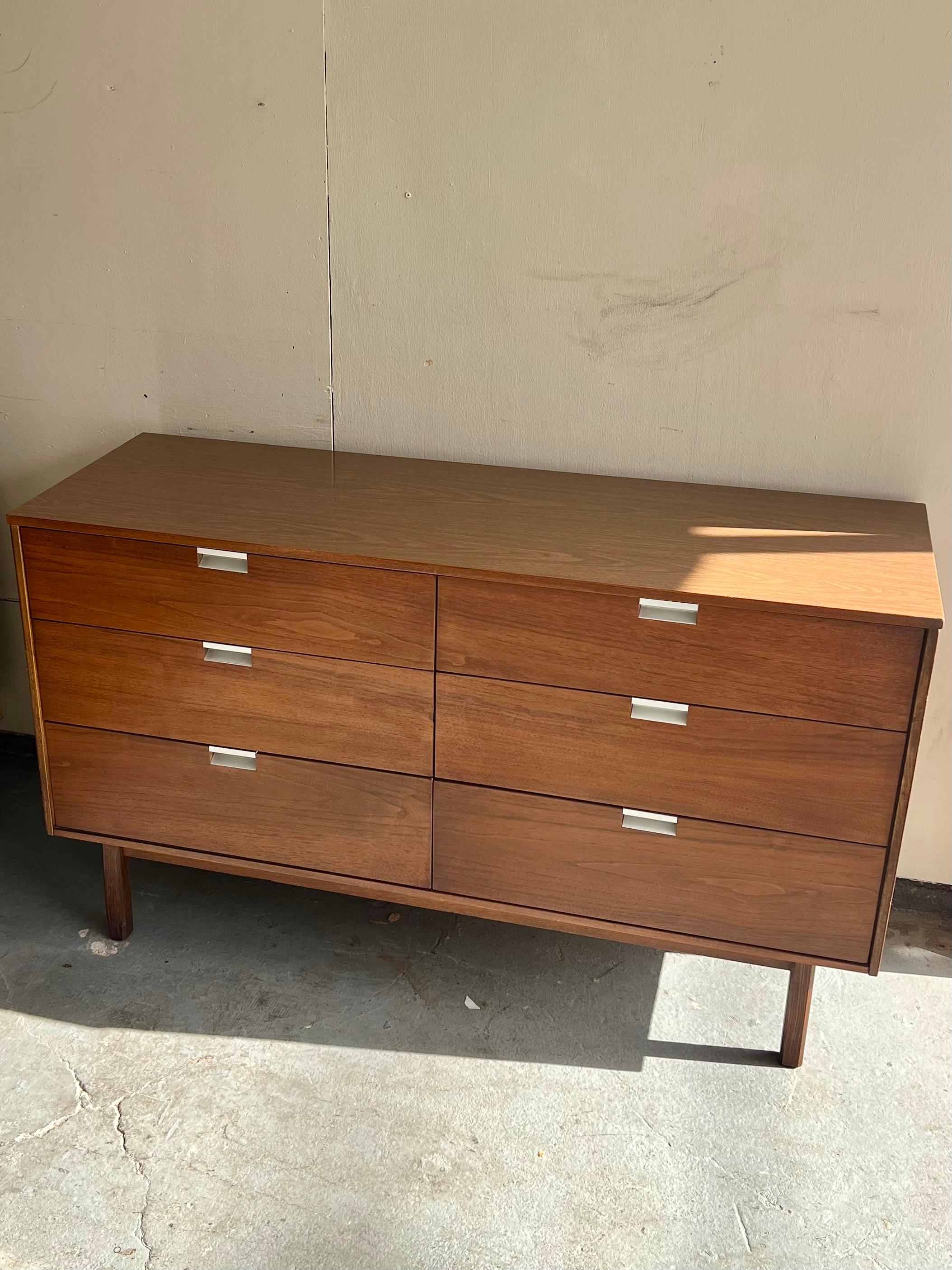 A sleek compact lowboy feating six drawers with recessed stainless pulls reminiscent of the designs of George Nelson. All drawers slide smoothly on wooden tracks. Minimal wear. Two small walnut veneer chips have been filled- please see photos. Some