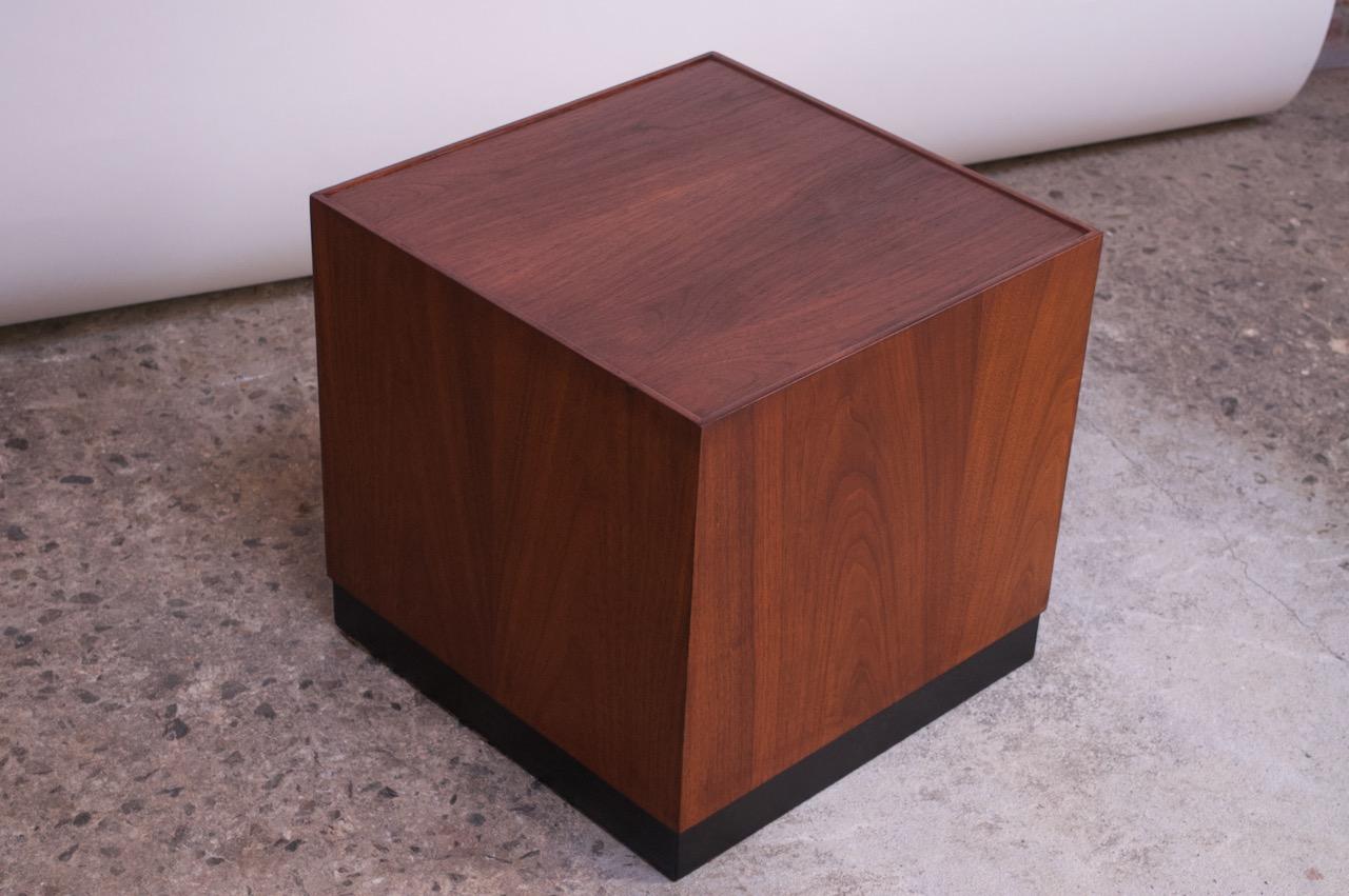 Low, cube end / side table (circa 1960s, USA) in walnut with an ebonized plinth-base. Finished on all sides, each with different walnut grain. Refinished condition; only minor wear remains (one small repair to replace a spot of veneer loss).