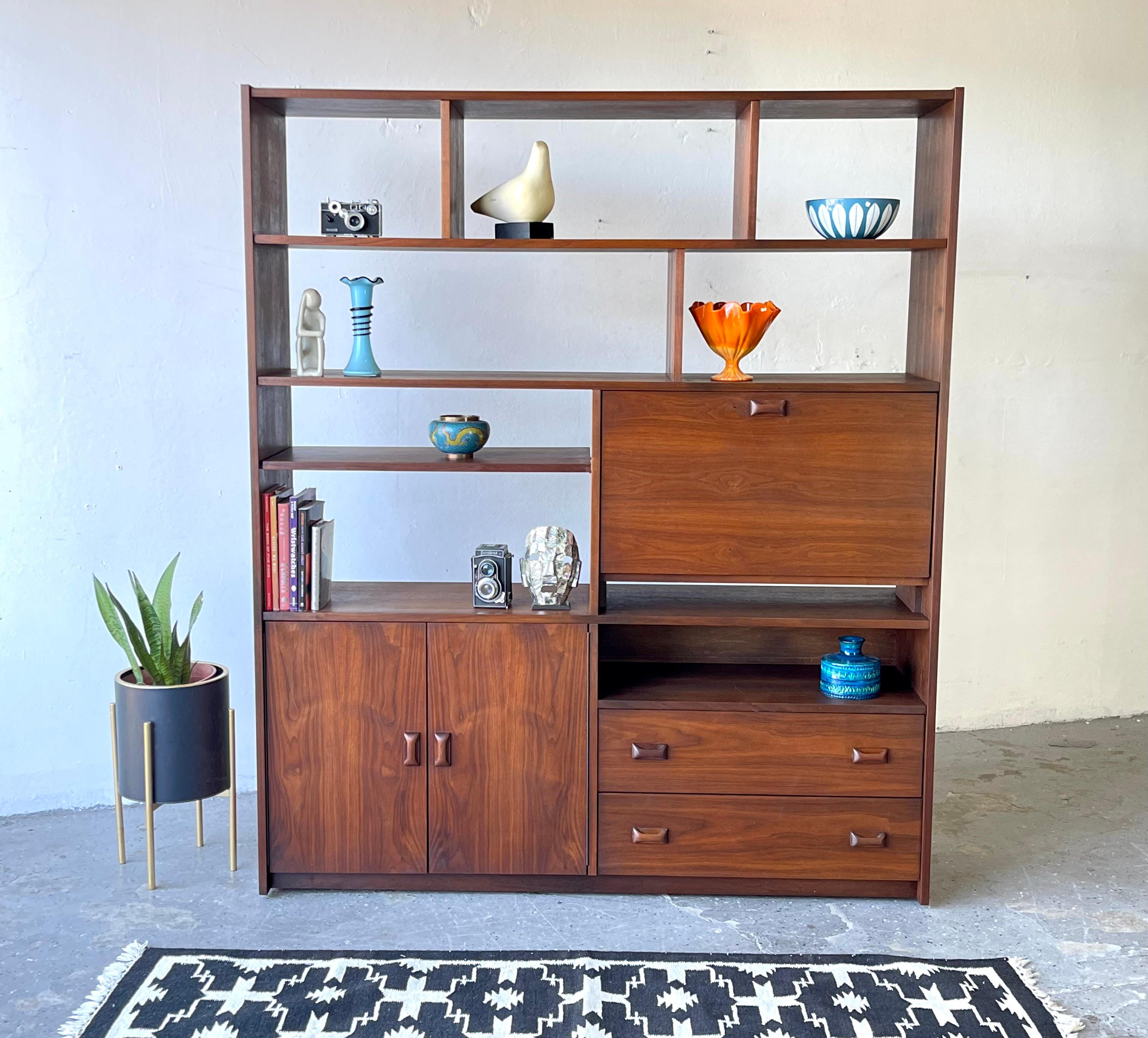 This is a big, beautiful, mid-century room divider in rich, warm walnut. It is finished on both sides, so it can be used against the wall as a bookcase or in the middle of the room as a divider. The door on the top compartment flips down on a piano