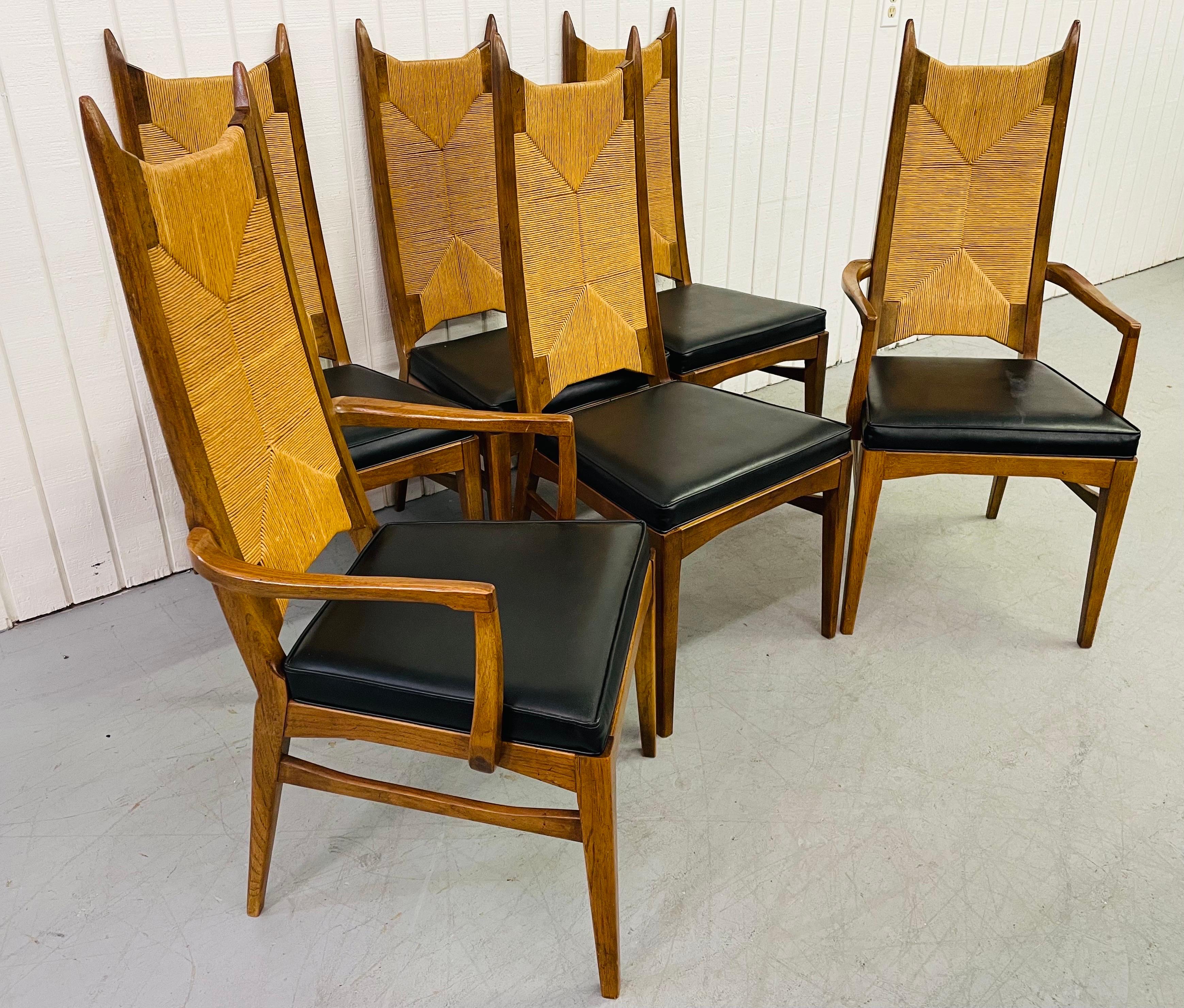 This listing is for a set of six mid-century walnut dining chairs. Featuring a rush back design, spear shaped tops, black leather seats, and a light walnut finish.