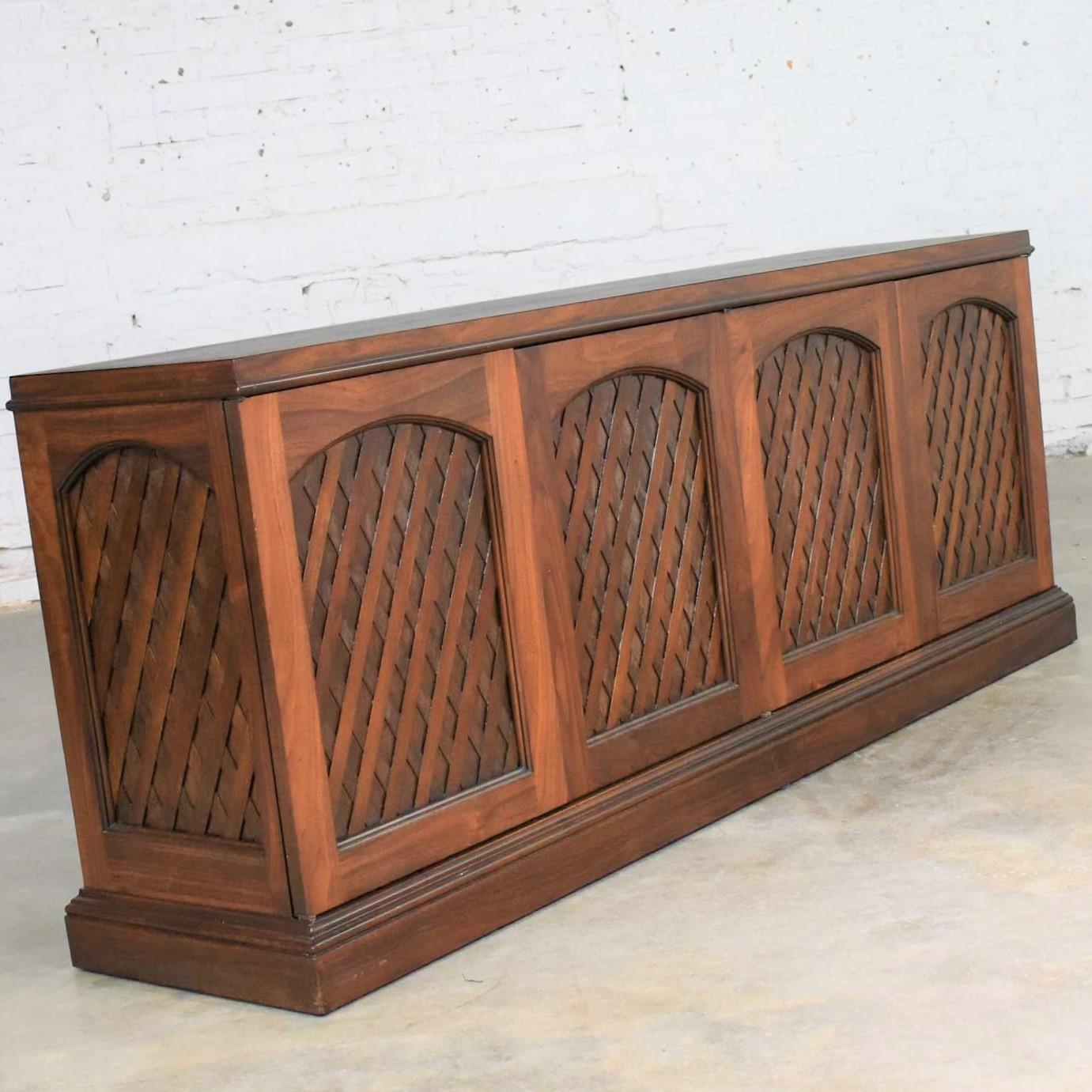 Handsome midcentury walnut shallow depth credenza with a diamond lattice pattern panel design. It is in wonderful condition. We have done a partial restoration to some of its finish but left some of the natural age distressing on the lattice panels