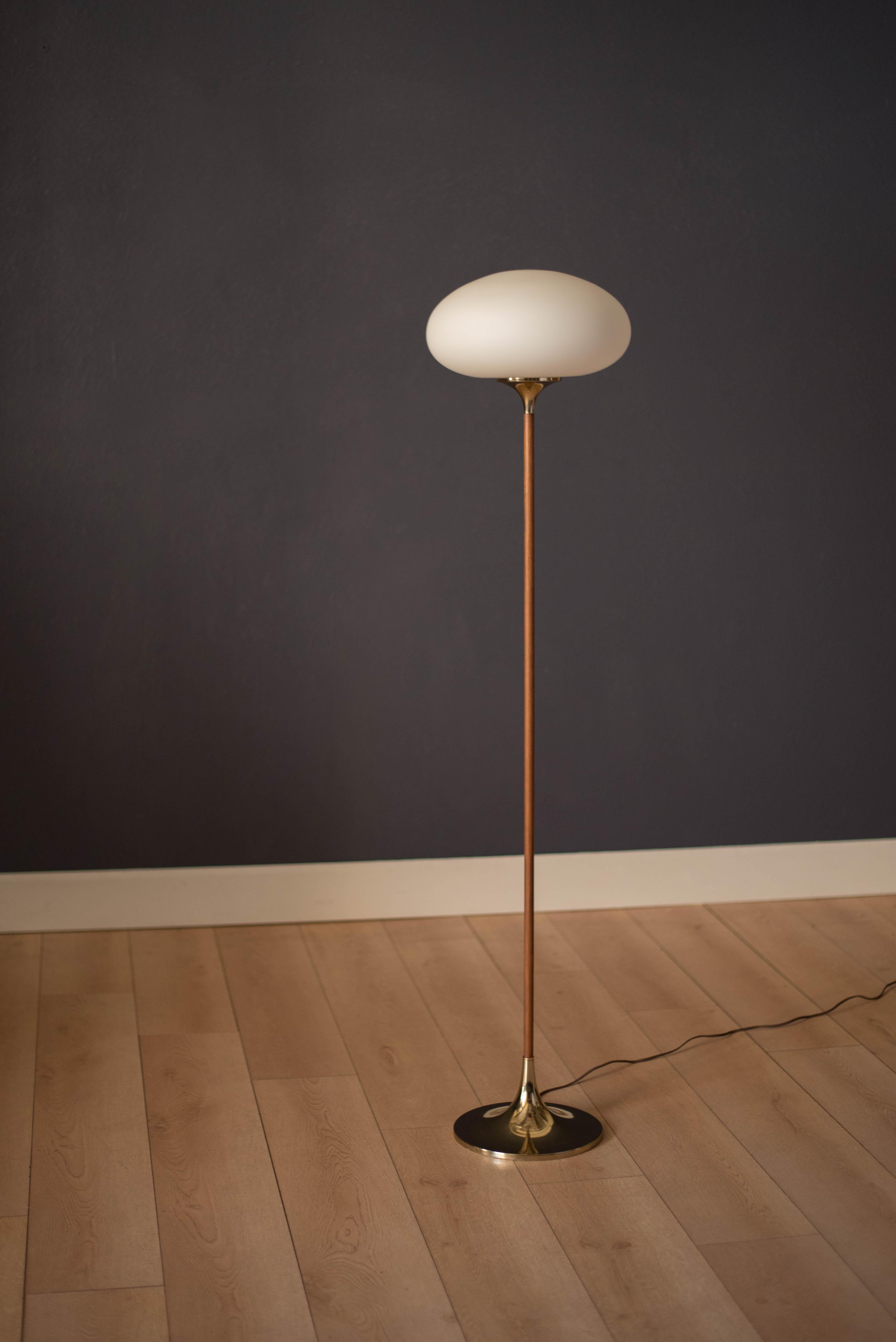 Mid-Century Modern floor lamp by Laurel Lamp Co. This piece emits light with a glowing mushroom frosted globe shade. Features a walnut stem and a sculptural brass base. Functions with a three-way switch.