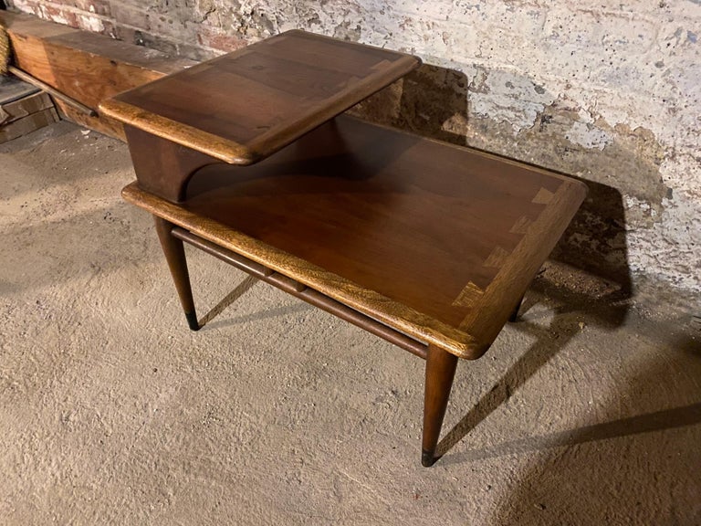 Mid-century walnut step table by Lane, Acclaim. Two-tiered walnut side table by Lane Furniture, part of the Acclaim line designed by Andre Bus showcasing his iconic two-tone wood dovetail, using walnut and fruit woods. Beautiful wood tone and black