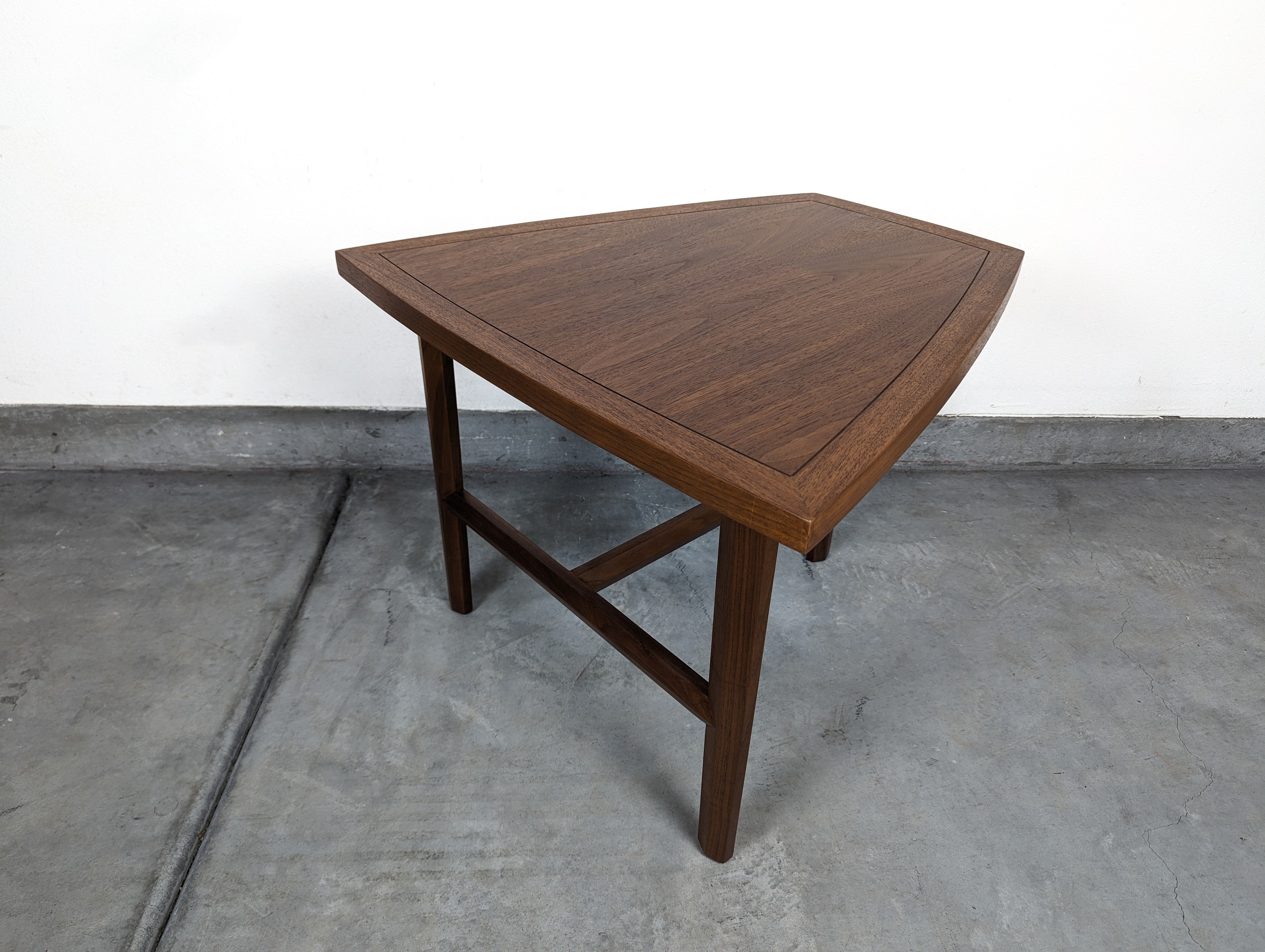 Step into the realm of mid-century modern design with this exquisitely crafted walnut side table, a testament to the ingenuity of renowned master woodworker George Nakashima. A part of the Widdicomb collection dating back to the 1960s, this table