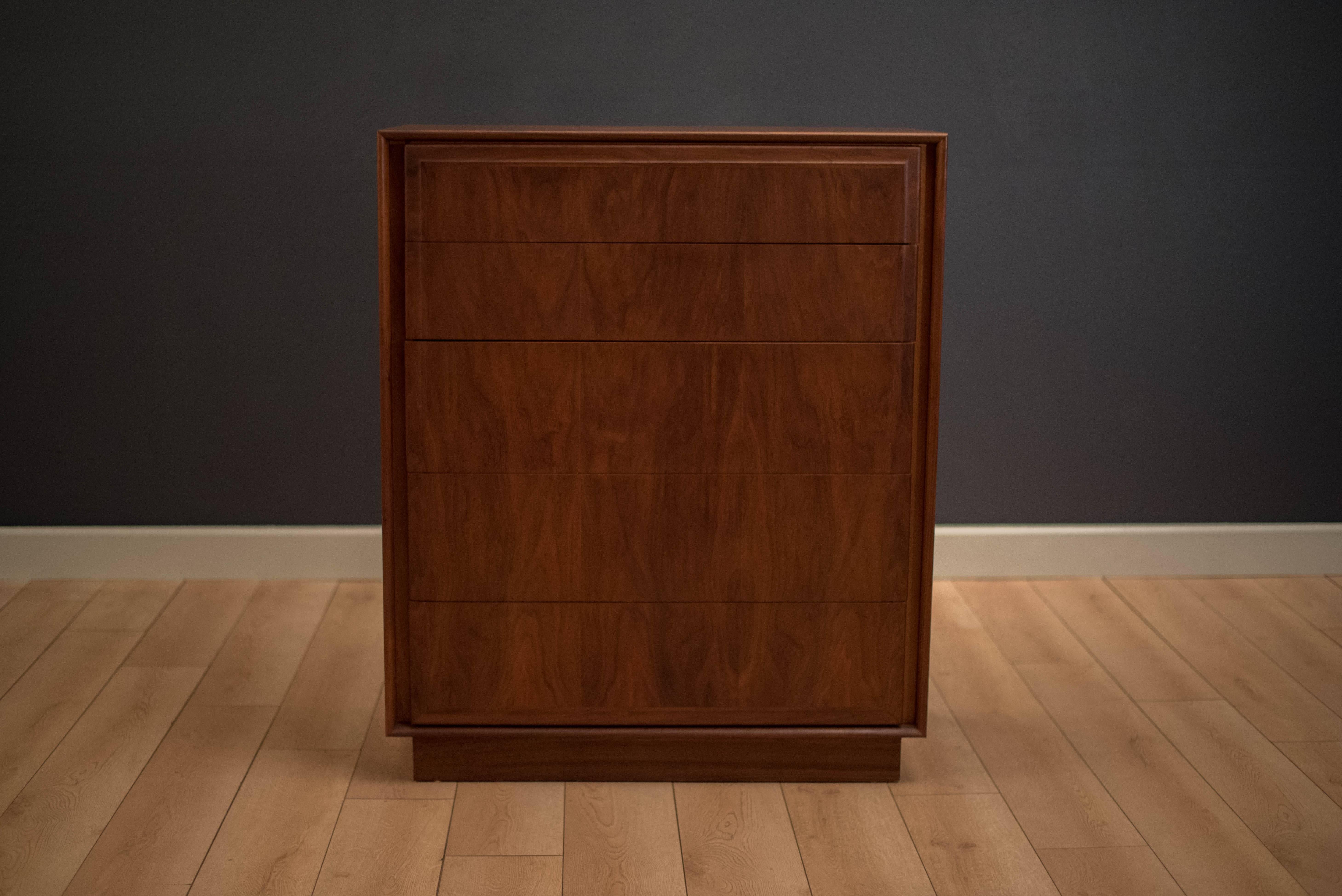 Mid-Century Modern highboy dresser in walnut manufactured by Dillingham Furniture. This piece includes plenty of storage with five dovetailed drawers. Displays a natural walnut finish and sits on an inset plinthe base. Matching pair of nightstands