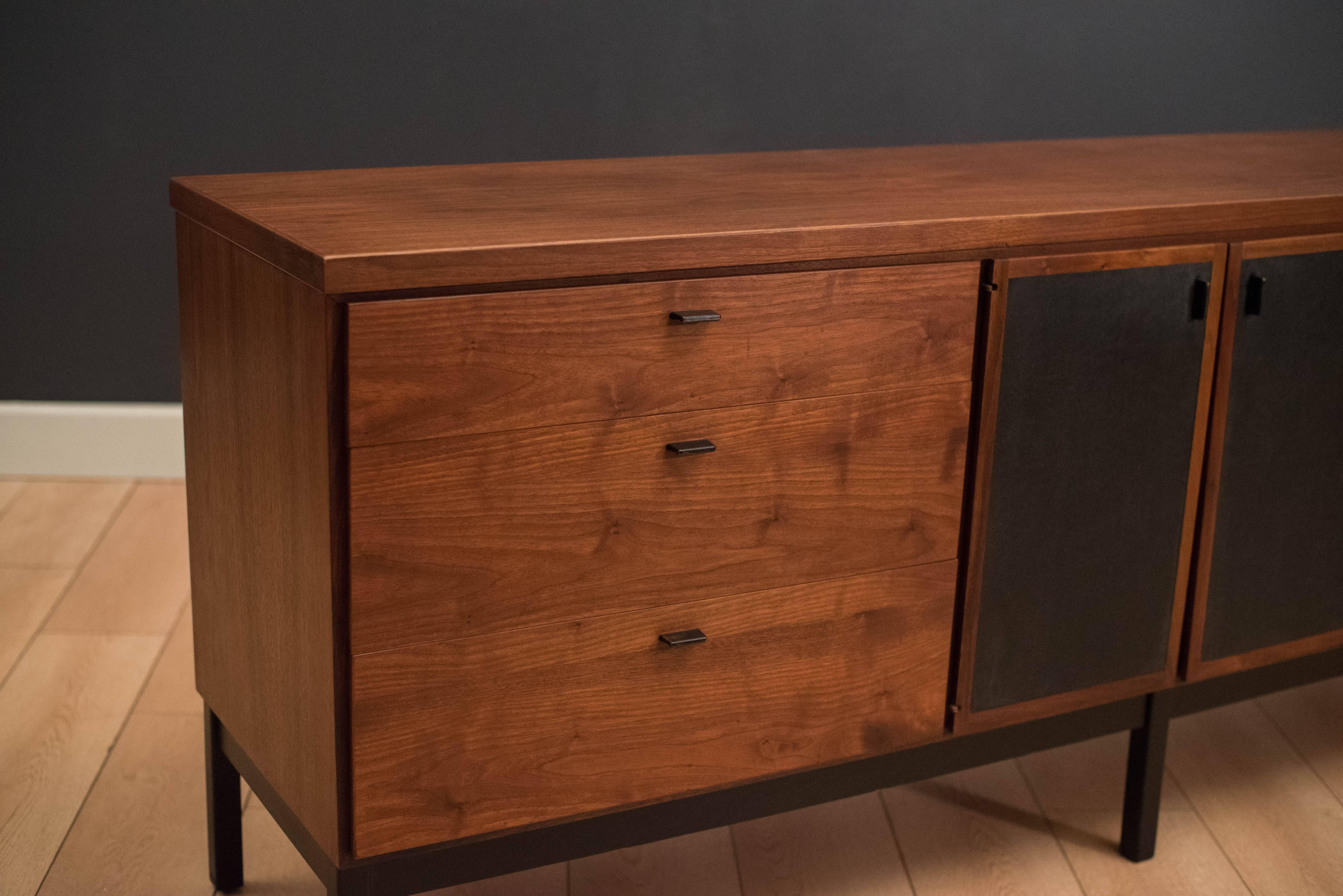 Mid-Century Modern dresser in walnut. This piece includes nine storage drawers with black metal pulls. Swing out doors are lined with black vinyl. Matching nightstands and tall dresser available in separate listing.