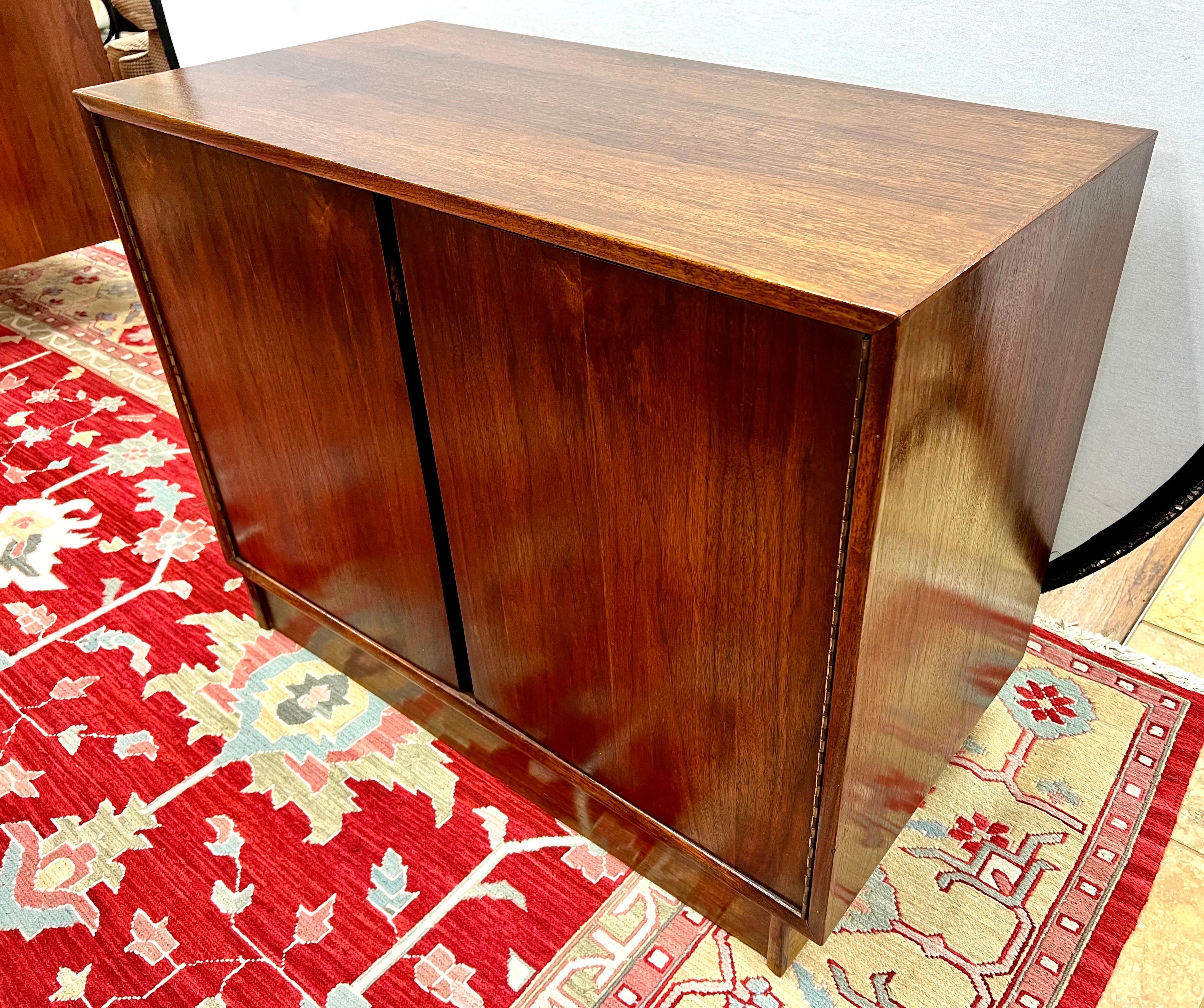 Mid-century walnut two door cabinet. Multipurpose use as a dry bar, sideboard or entertainment cabinet. Has been polished to bring out beautiful wood graining. Great scale for apartment or smaller space and better lines.