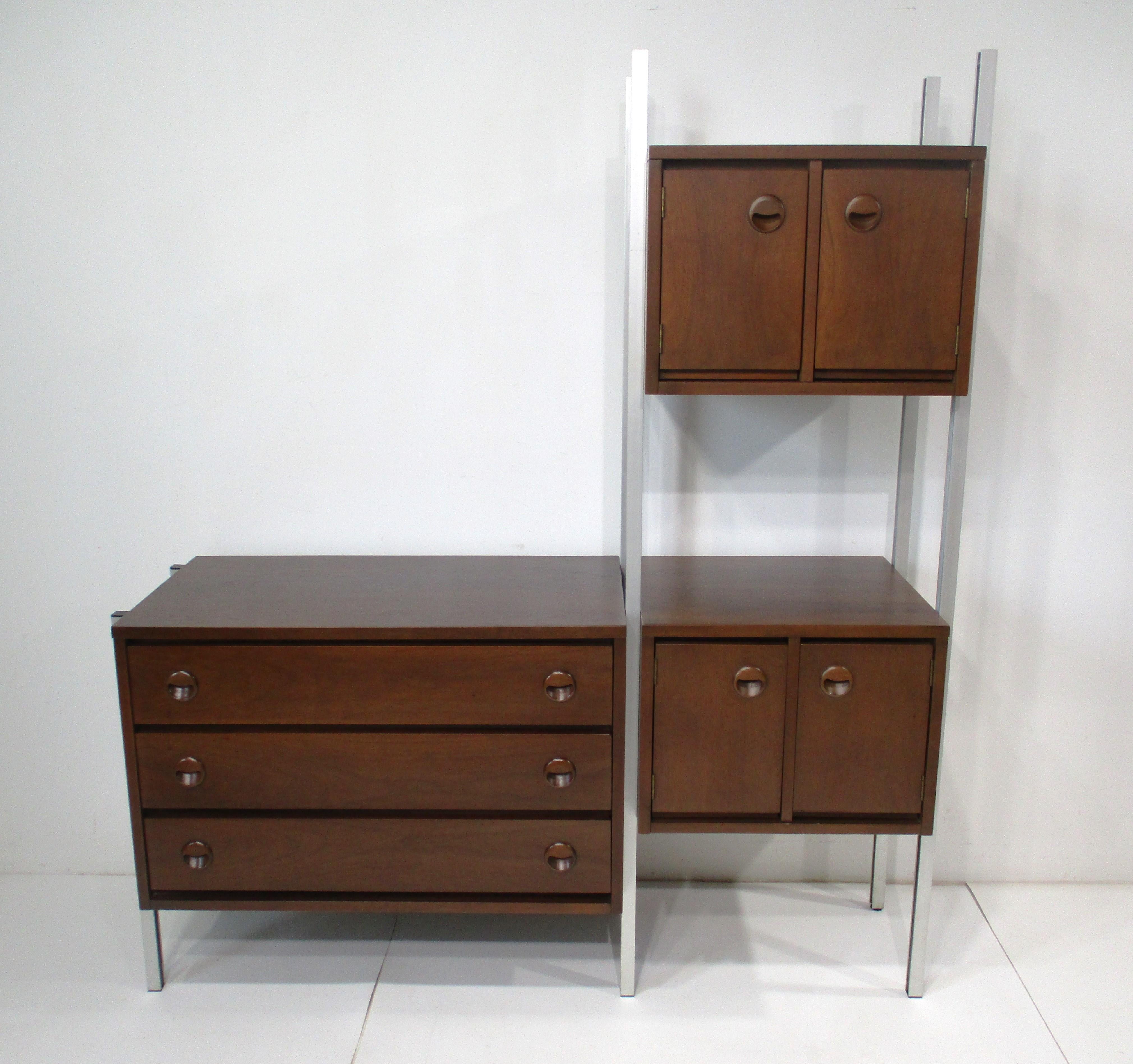 Un mobile a parete di dimensioni ridotte, in stile Mid Century, che può stare in piedi da solo con il retro completamente rifinito. Questo pezzo di ottima fattura è in noce scuro, con tiretti scultorei e telaio in alluminio spazzolato. Una