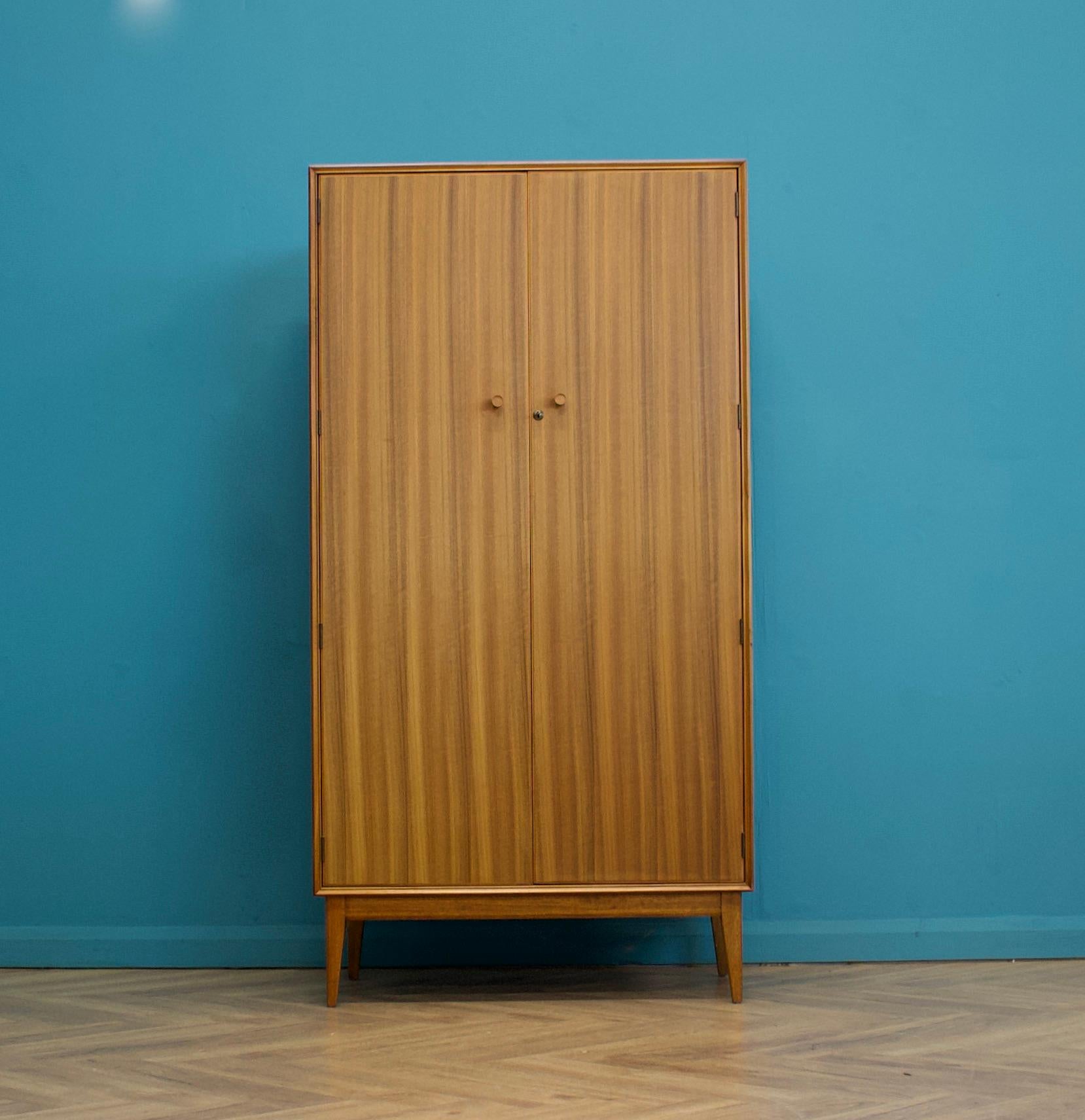 A walnut freestanding three door wardrobe by Alfred Cox - these pieces were usually retailed through Heals department store during the 1950s and 1960s
Internally there is a hanging rail and shelves
The attractive legs are slightly tapered and
