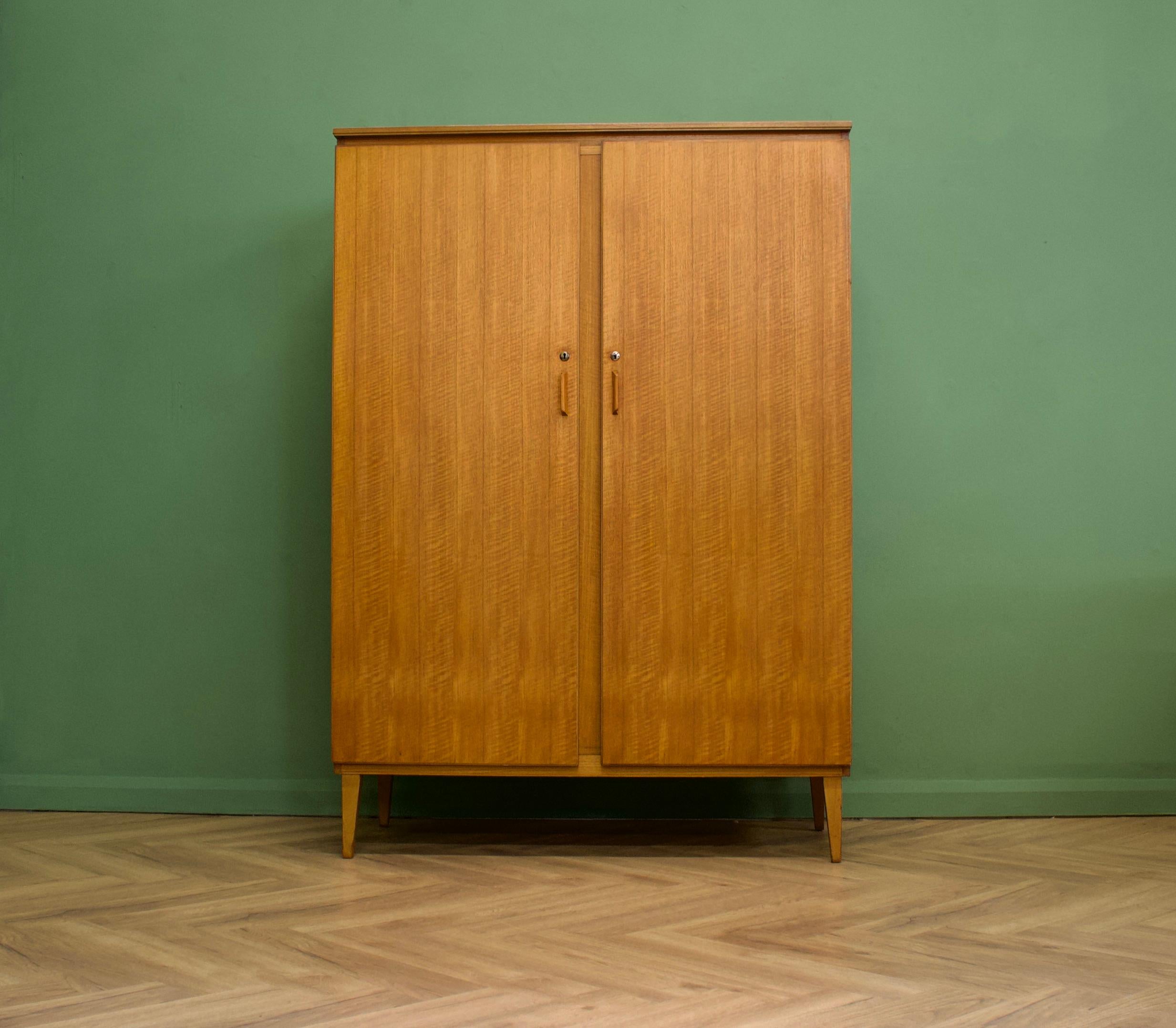 A walnut freestanding wardrobe by Alfred Cox - these pieces were usually retailed through Heals department store during the 1950s and 1960s
Internally there are two hanging rails and a shelf
The attractive legs are slightly tapered and splayed and