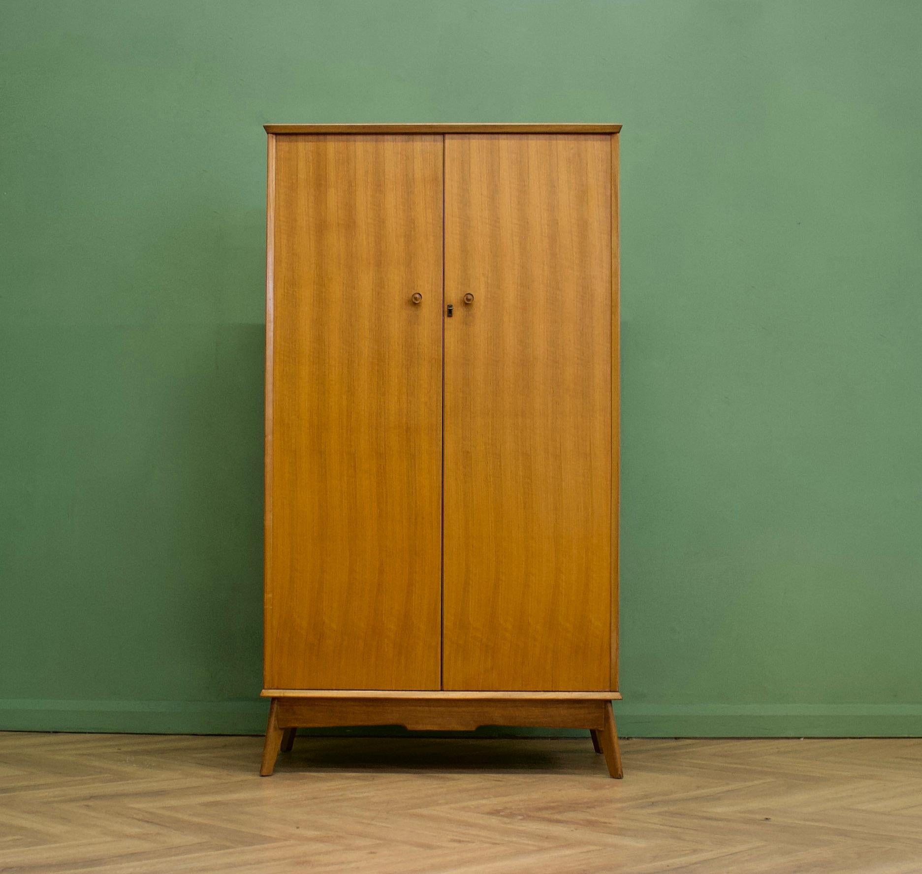 Ein freistehender Kleiderschrank aus Nussbaumholz von Alfred Cox - diese Stücke wurden in den 1950er und 1960er Jahren in der Regel über das Kaufhaus Heals's vertrieben
Im Inneren befinden sich eine Kleiderstange und Regale.
Die attraktiven Beine