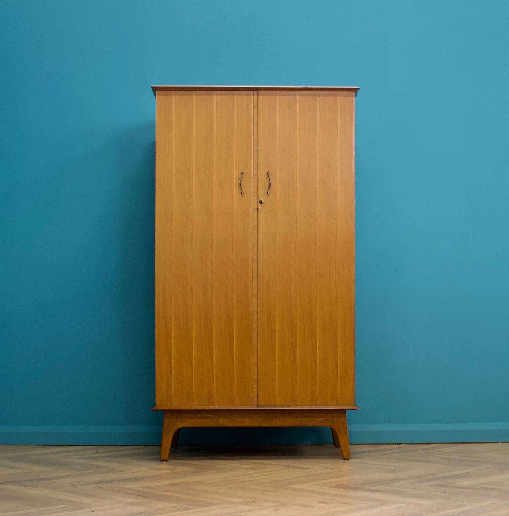 A walnut freestanding wardrobe by Alfred Cox - these pieces were usually retailed through Heals department store during the 1950s and 1960s
Internally there is a hanging rail and shelves
The attractive legs are splayed and the handles are solid wood