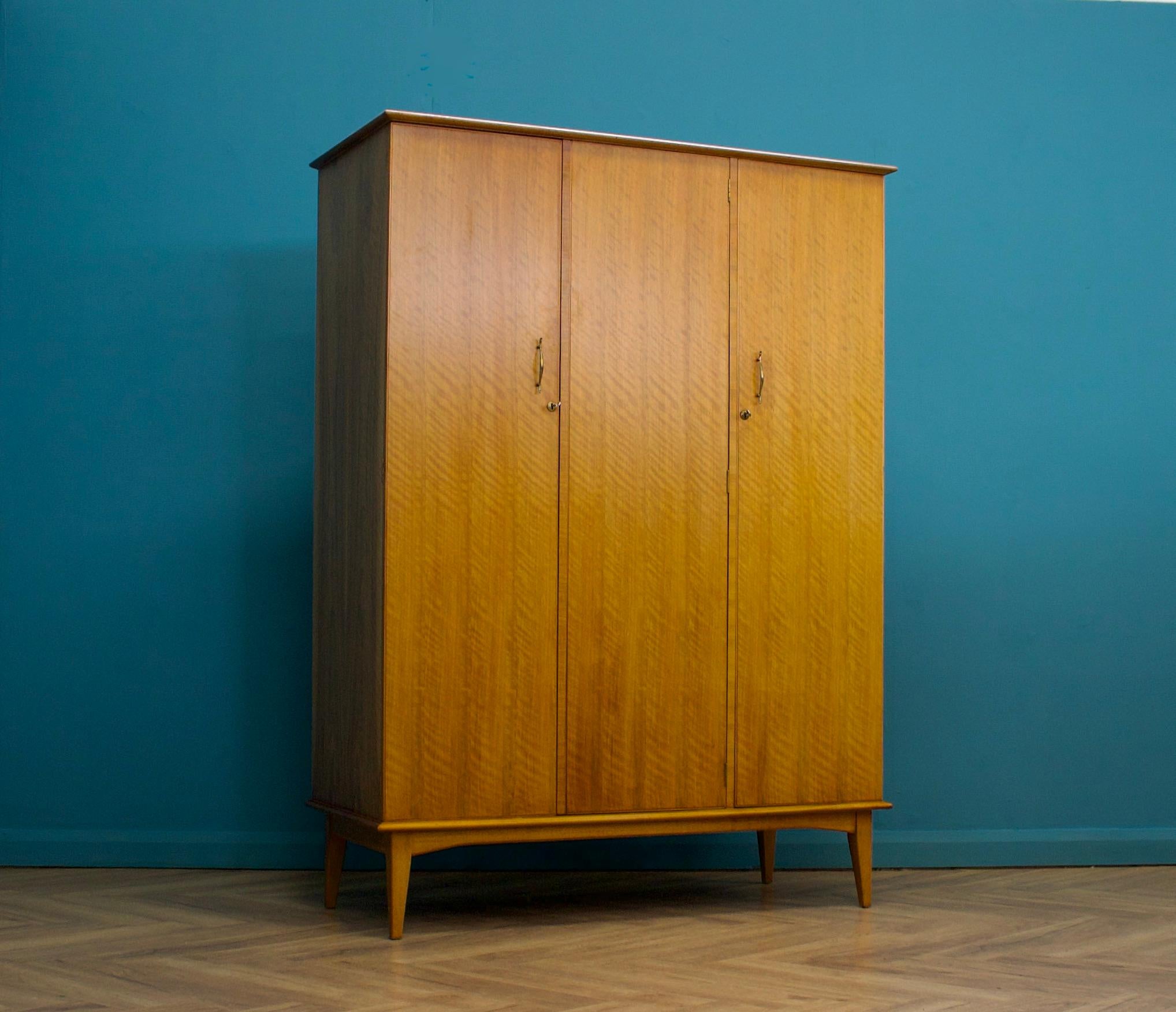 A walnut freestanding three door wardrobe by Alfred Cox - these pieces were usually retailed through Heals department store during the 1950s and 1960s
Internally there are two hanging rails and a shelf
The attractive legs are slightly tapered and