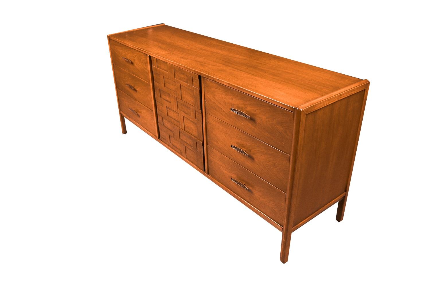 An elegant long nine drawer dresser. This is a beautiful example of Mid-Century craftsmanship. This retro piece was constructed with top of the line hardware, and excellently crafted woodwork. Features solid hardwood, with walnut and weave pattern