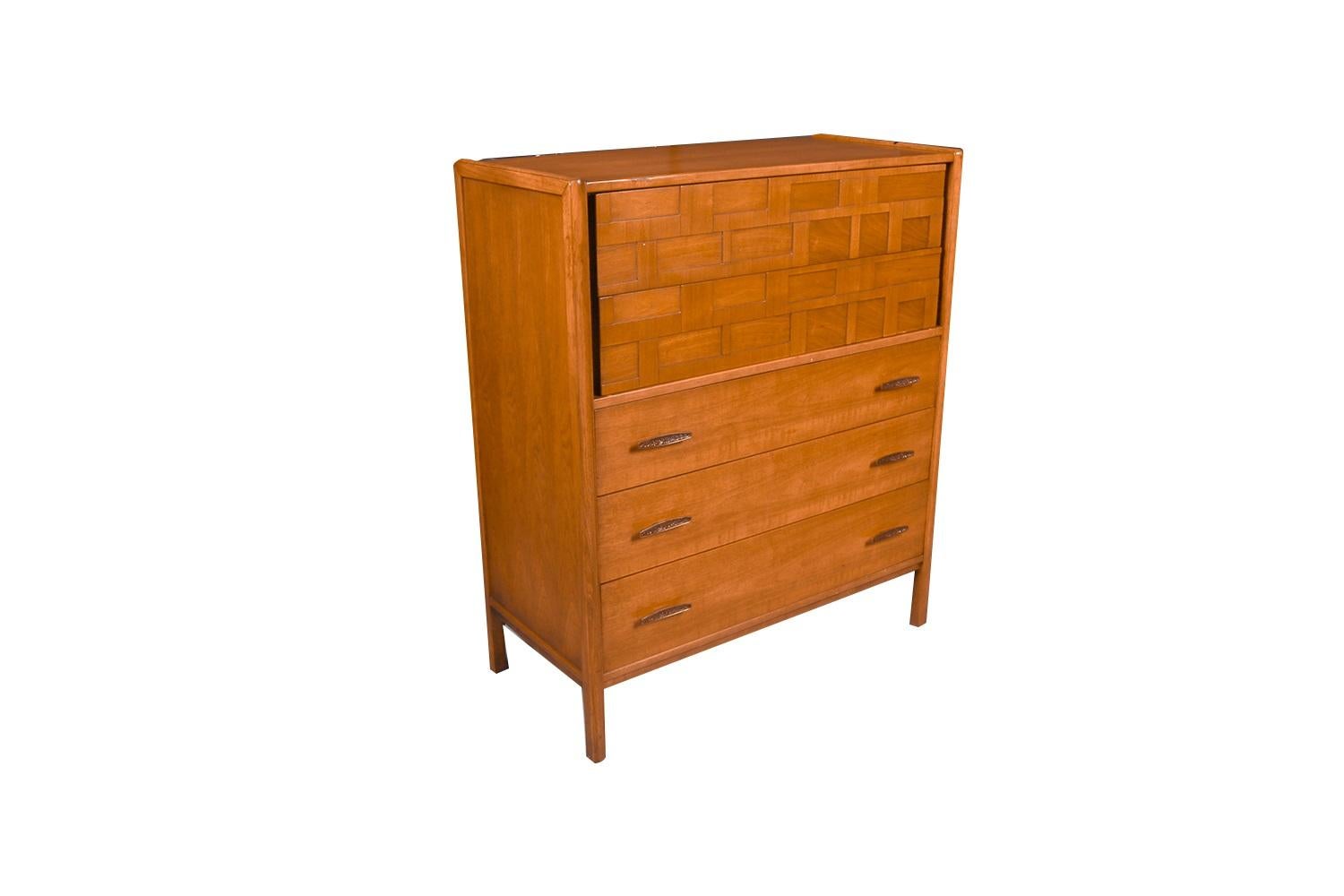 An elegant tallboy dresser. This is a beautiful example of Mid-Century craftsmanship. This retro piece was constructed with top of the line hardware, and excellently crafted woodwork. Features solid hardwood, with walnut and weave pattern finish.