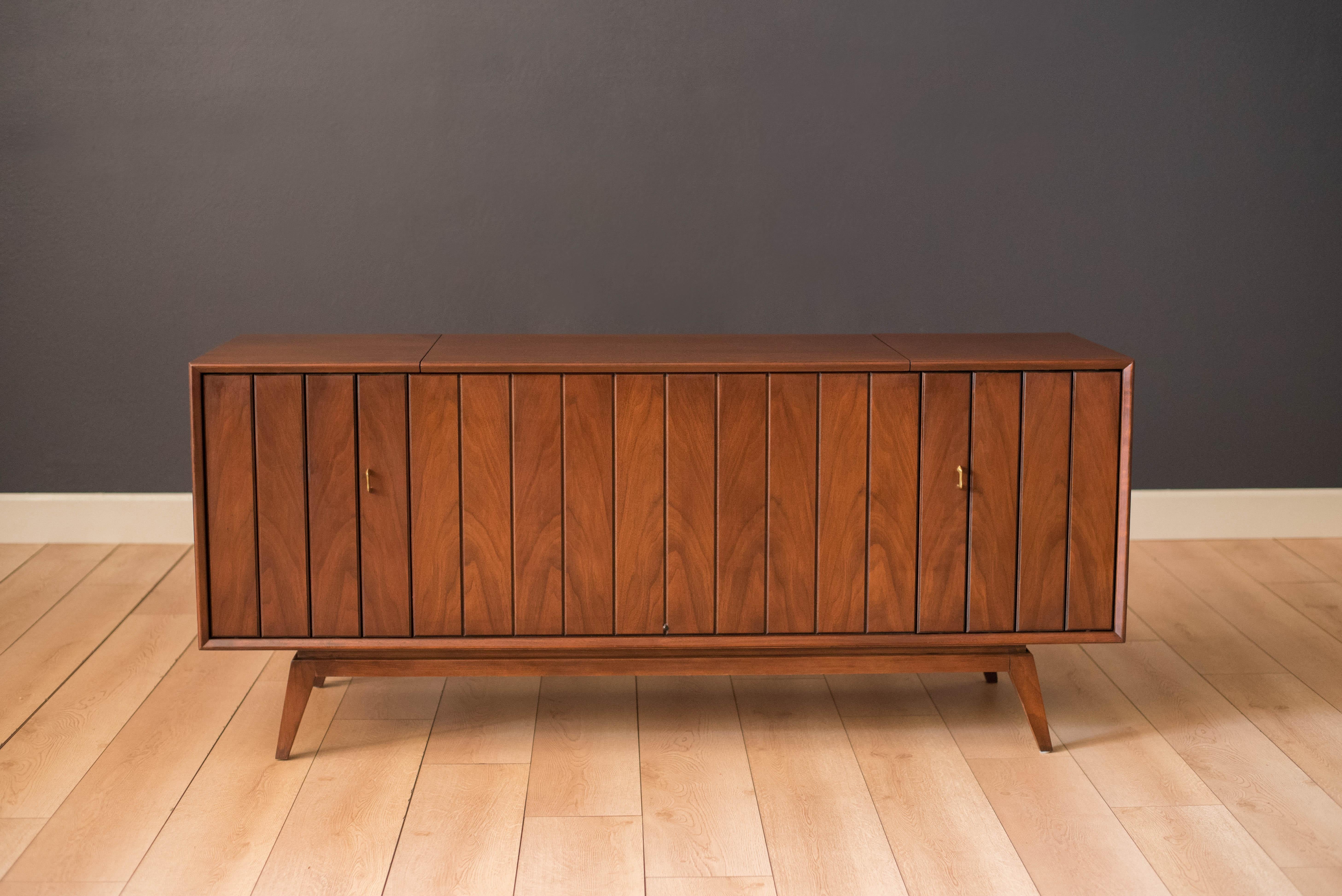 Vintage Zenith Solid State Record console cabinet in walnut, circa 1960s. This piece includes a fully functional record player, AM/FM radio, speakers, and phonograph (not tested), complete with original manual. The cabinet features a stunning walnut