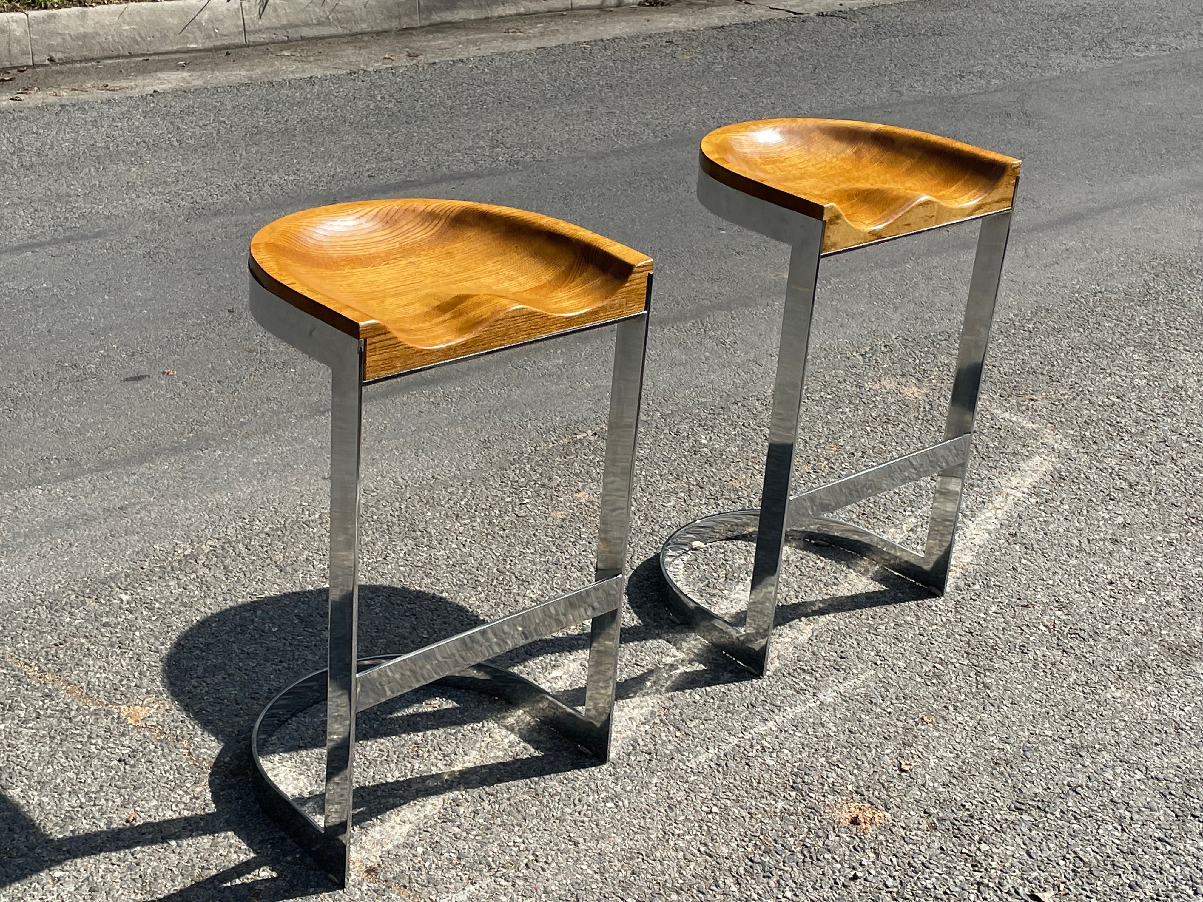 Pair of vintage Warren Bacon bar stools in solid chromed steel with carved wood saddle solid oak formed seat top. Circa 1970s.

Each bar stool measures 28