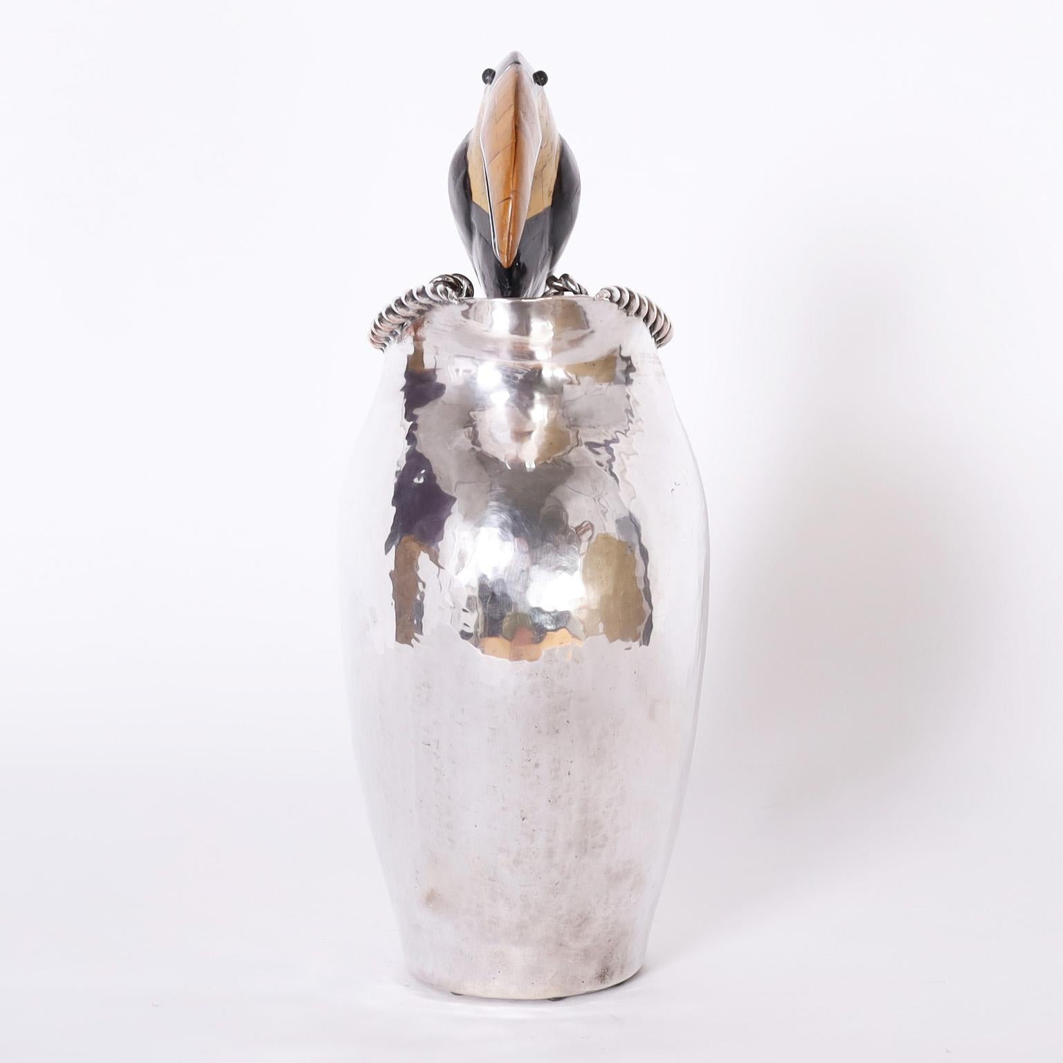 Water pitcher hand crafted by a master silversmith with copper and hand hammered to a graceful modern form, then silver plated. Featuring a toucan clad in exotic stones perched on top. Signed Emilia Castillo on the bottom.