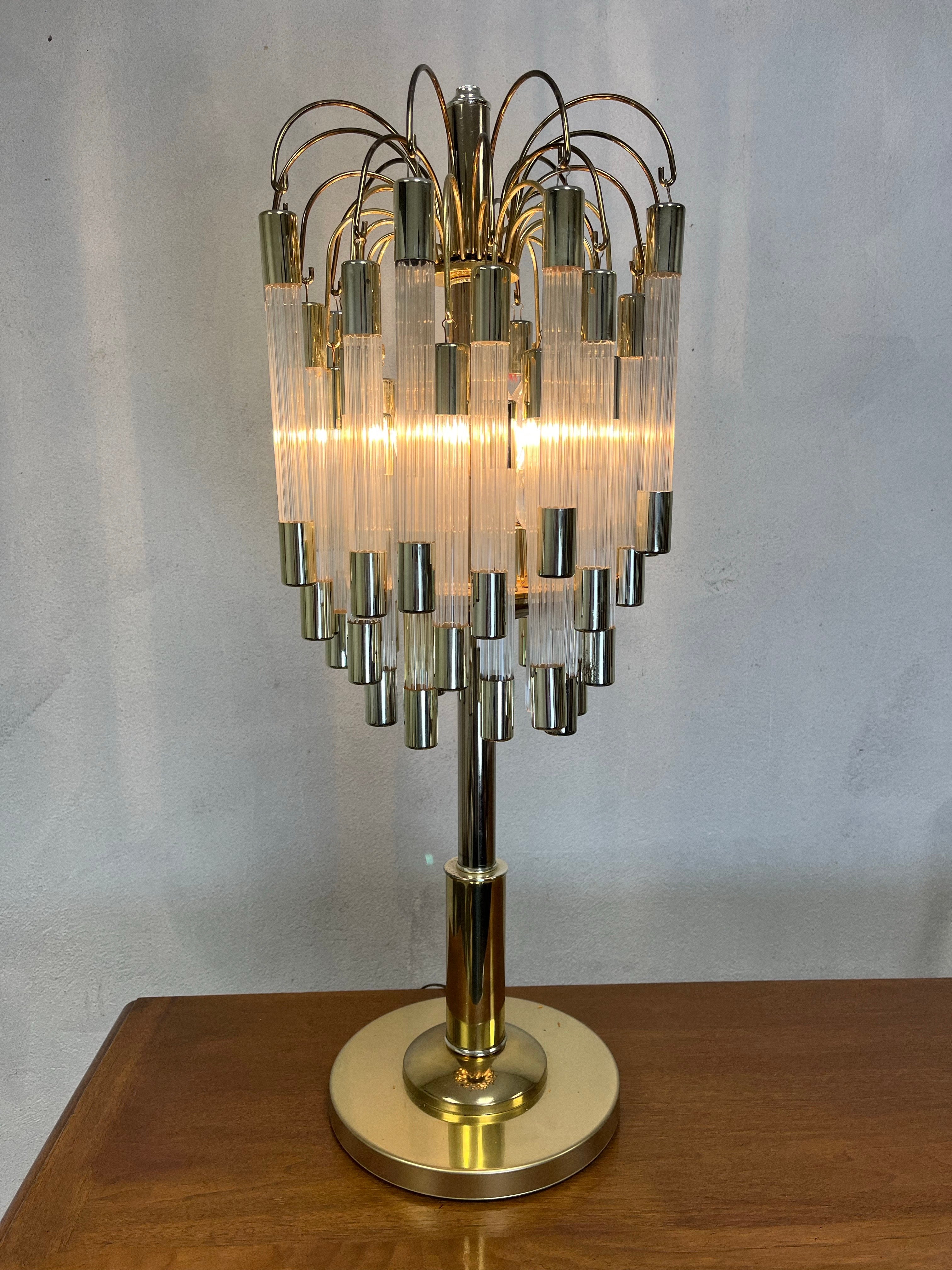 Bellissima lampada unica della metà del secolo scorso attribuita a Gaetano Sciolari. I CAP in metallo di tonalità ottone sostengono le aste cilindriche a coste in lucite/acrilico trasparente. Tre livelli di ganci a cui vengono appese le aste.