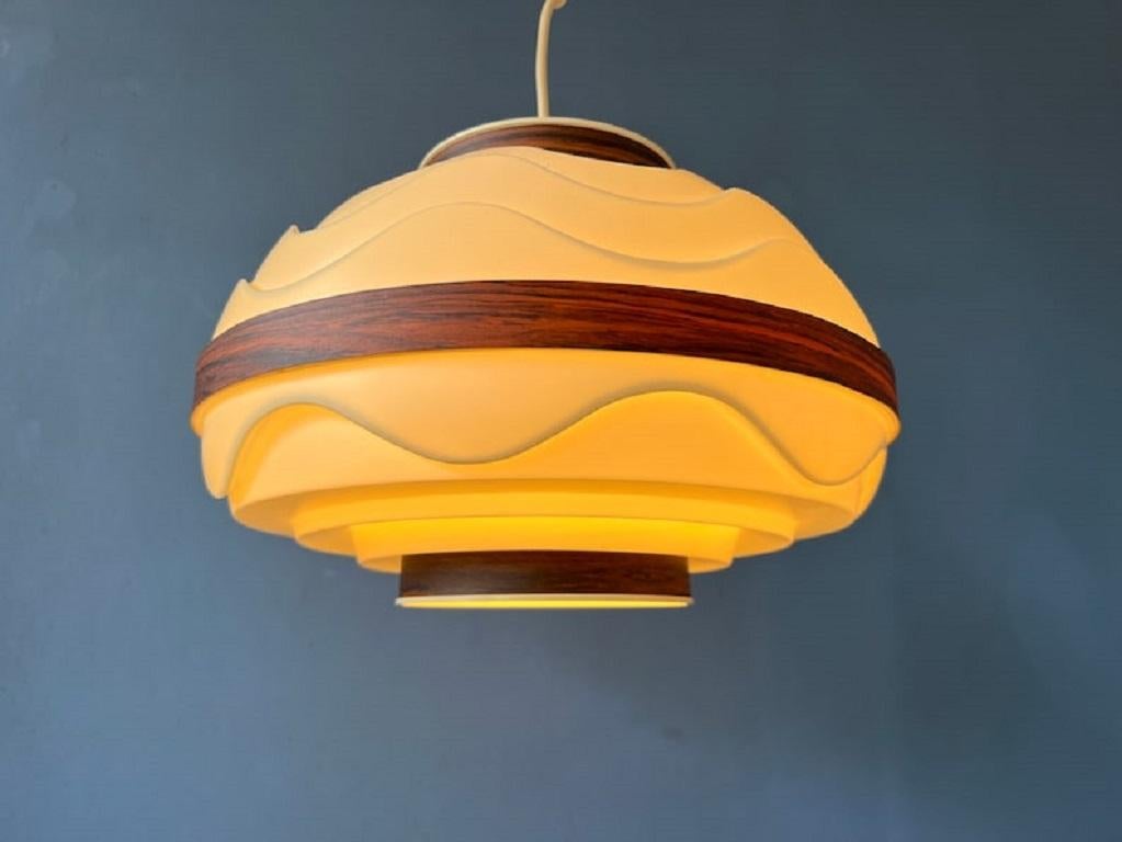Mid century scandinavian pendant lamp with a wavy structure. The lamp out is made out of beige, plastic material. This gives the lamp a light and airy feel. The lamp requires an E27/26 (standard) lightbulb.

Additional information:
Materials: Glass,