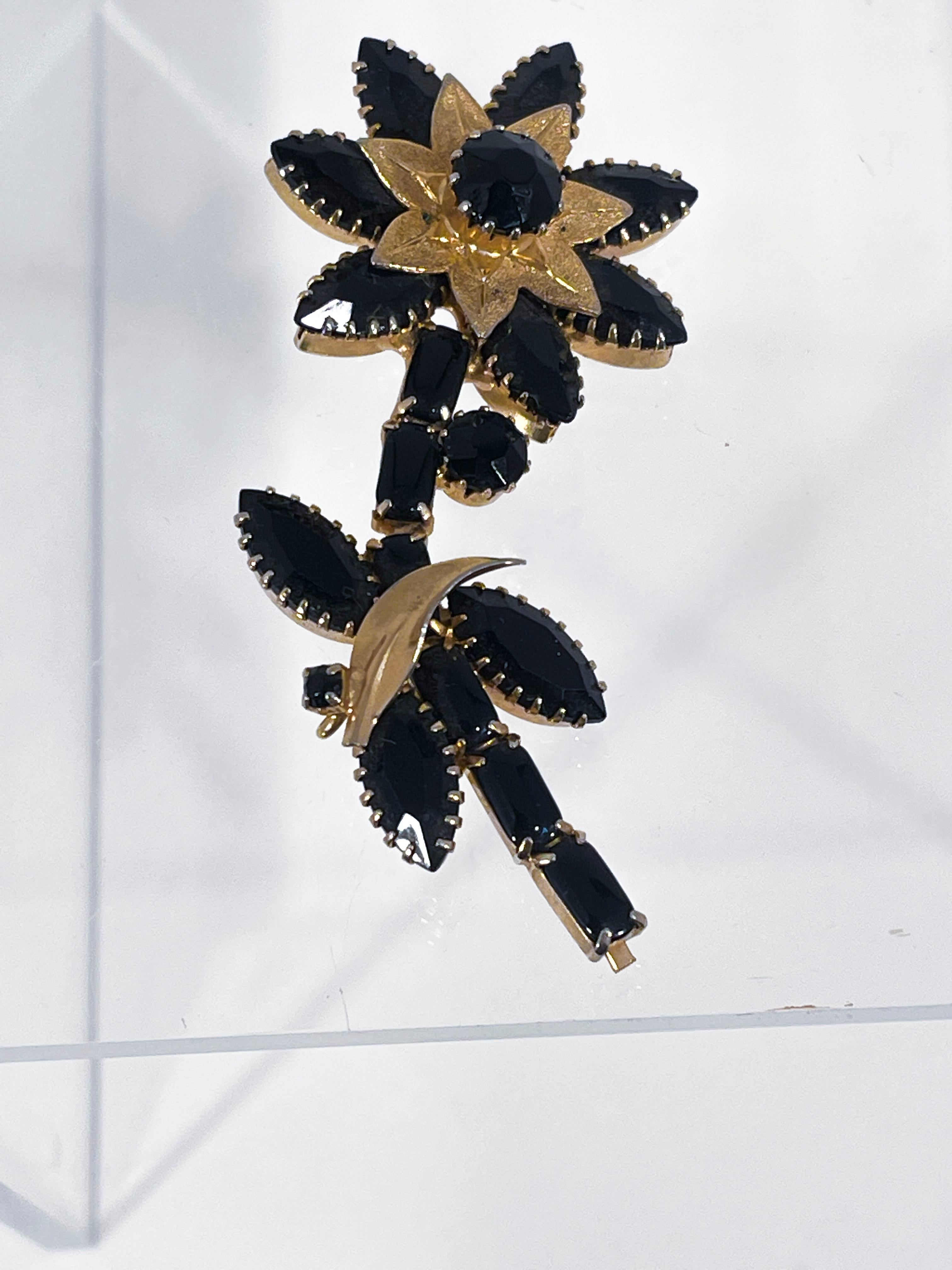 Mid-Century Weiss Daisy brooch with black rhinestones and gold-tone edging and leaf accents.