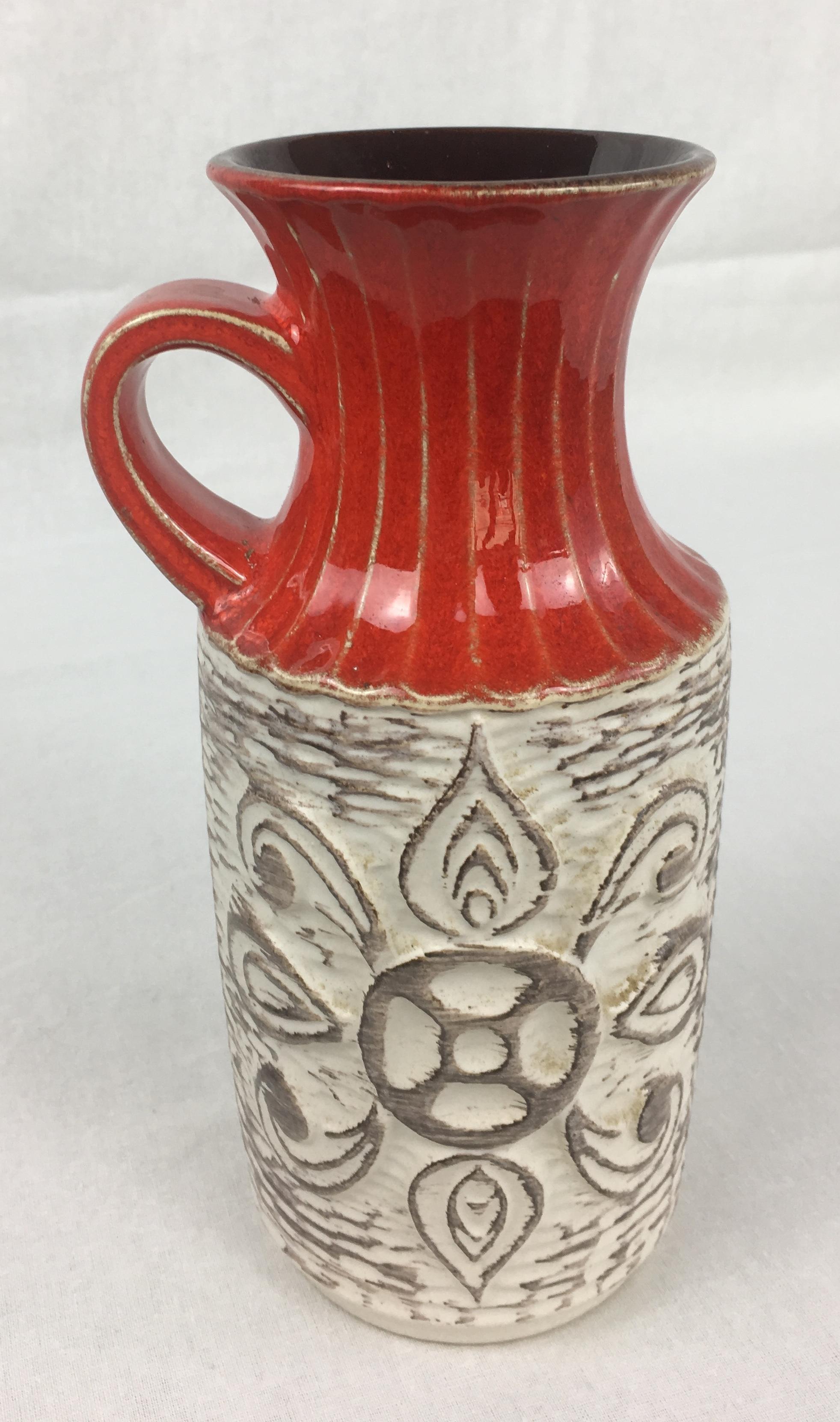 A fine Bay Keramik vase with stunning beige and red hues. This decorative object is unusual in the sense that it has a handle and the prominent carefully hand drawn designs of lines on the top in the red areas and centre scrolls make it particularly