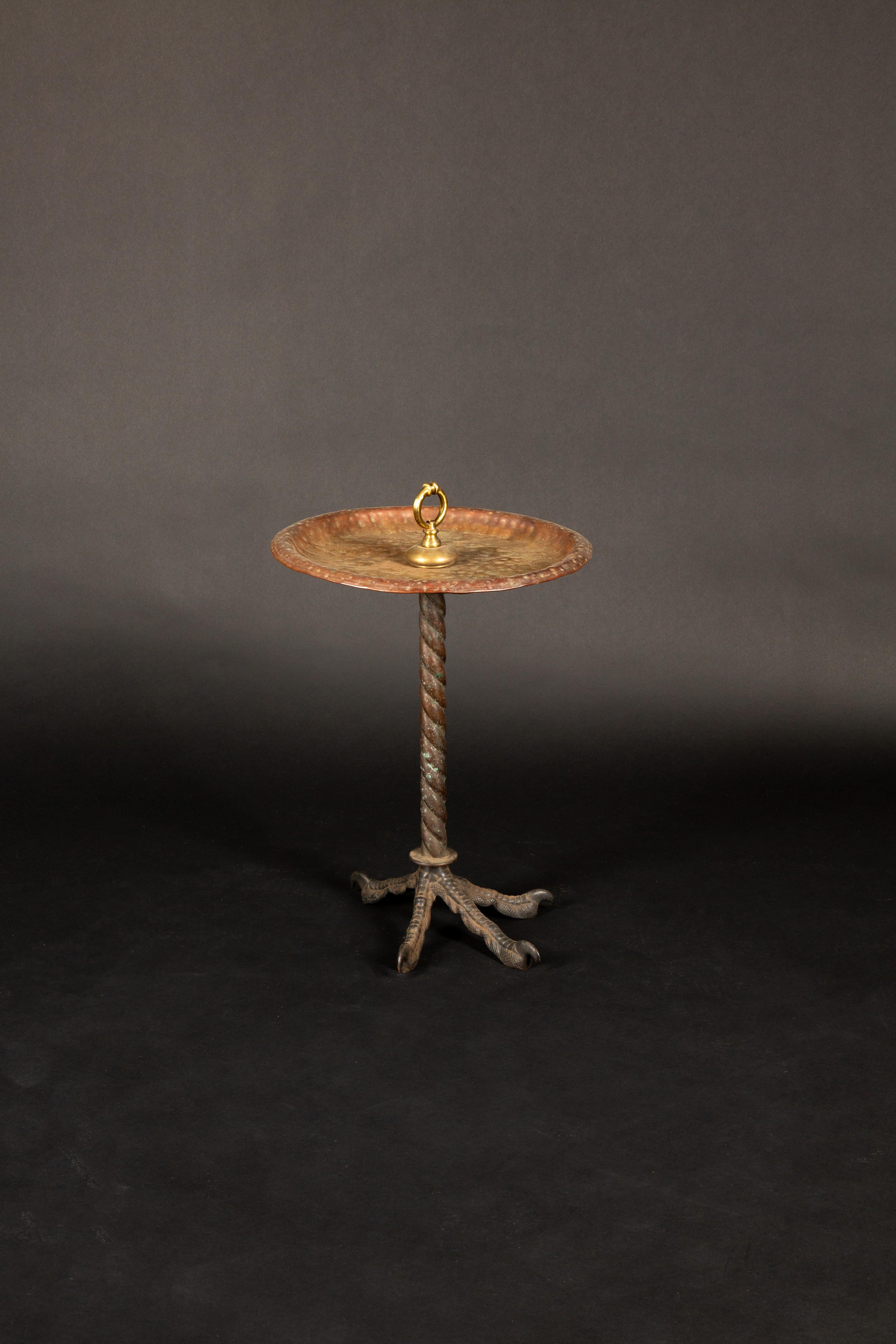 This mid-20th century side table showcases a whimsical design, blending artistry with function. The table's top is crafted from hammered copper, exuding a warm, rustic charm. Its standout feature is the base, intricately designed to resemble a