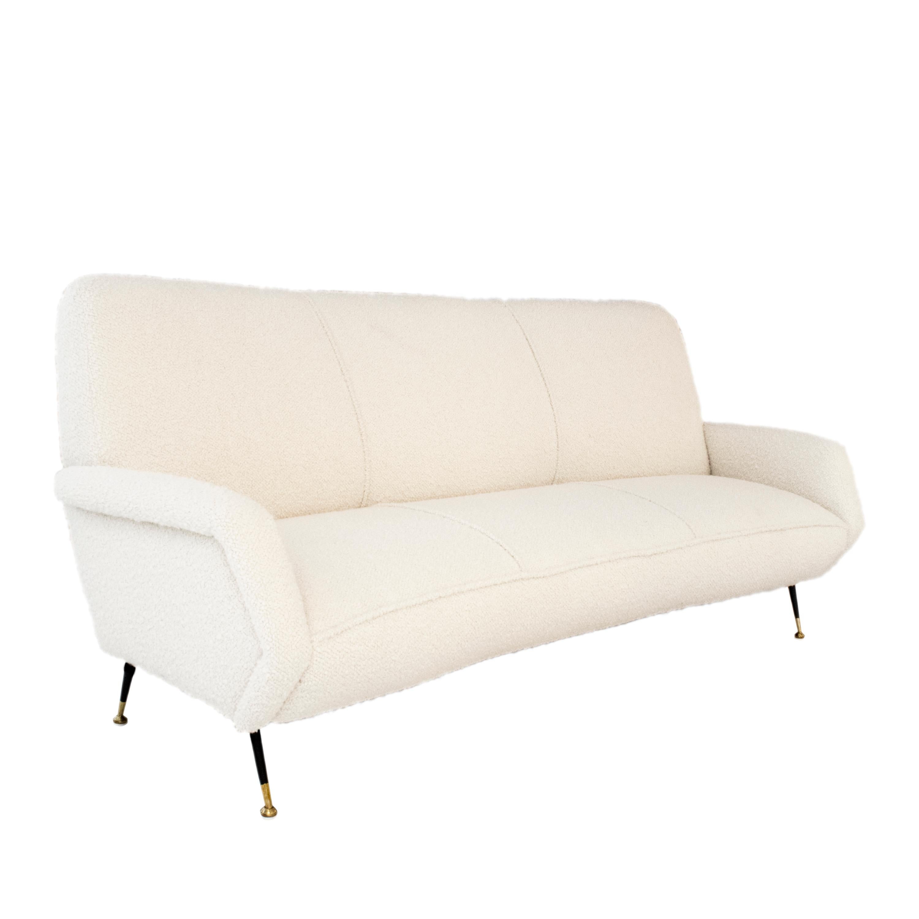 The white bouclé sofa is composed of a wooden structure and five metallic legs with brass details, upholstered in a white boucle. Made in Italy in the 1950's.

The white bouclé upholstery adds a touch of sophistication to the design, enhancing the