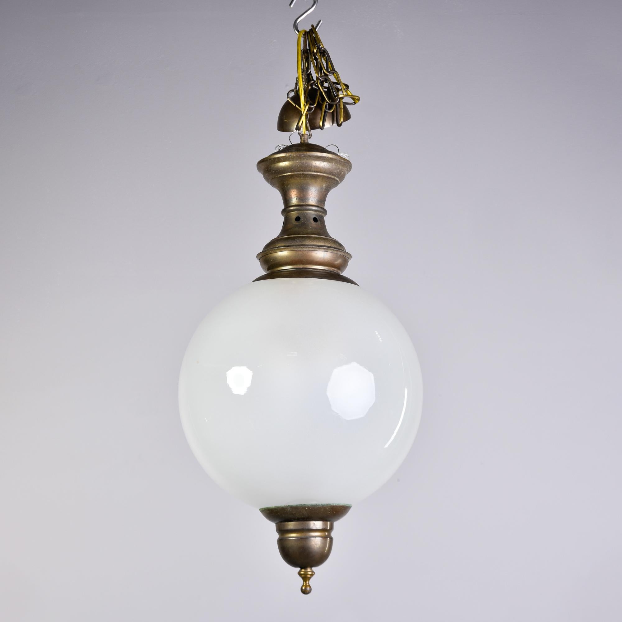 Found in Italy, this hanging pendant dates from approximately 1970. Round white glass globe with bronze fittings. Three interior standard sized sockets. Unknown maker. New wiring for US electrical standards. No flaws found.