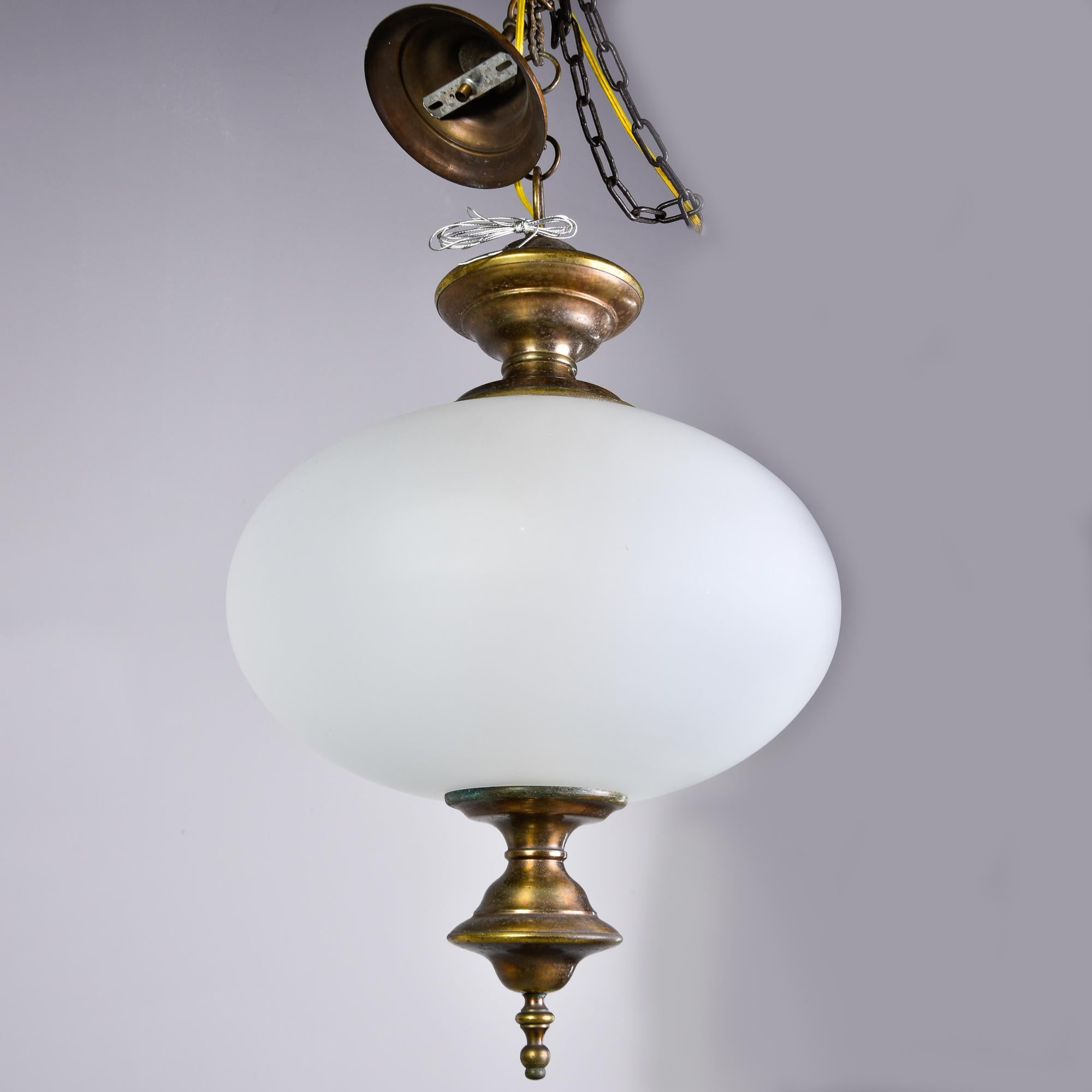 Found in Italy, this hanging pendant dates from approximately 1970. Squat, rounded white glass globe with bronze fittings. Three interior candelabra sockets. Unknown maker. New wiring for US electrical standards. No flaws found.