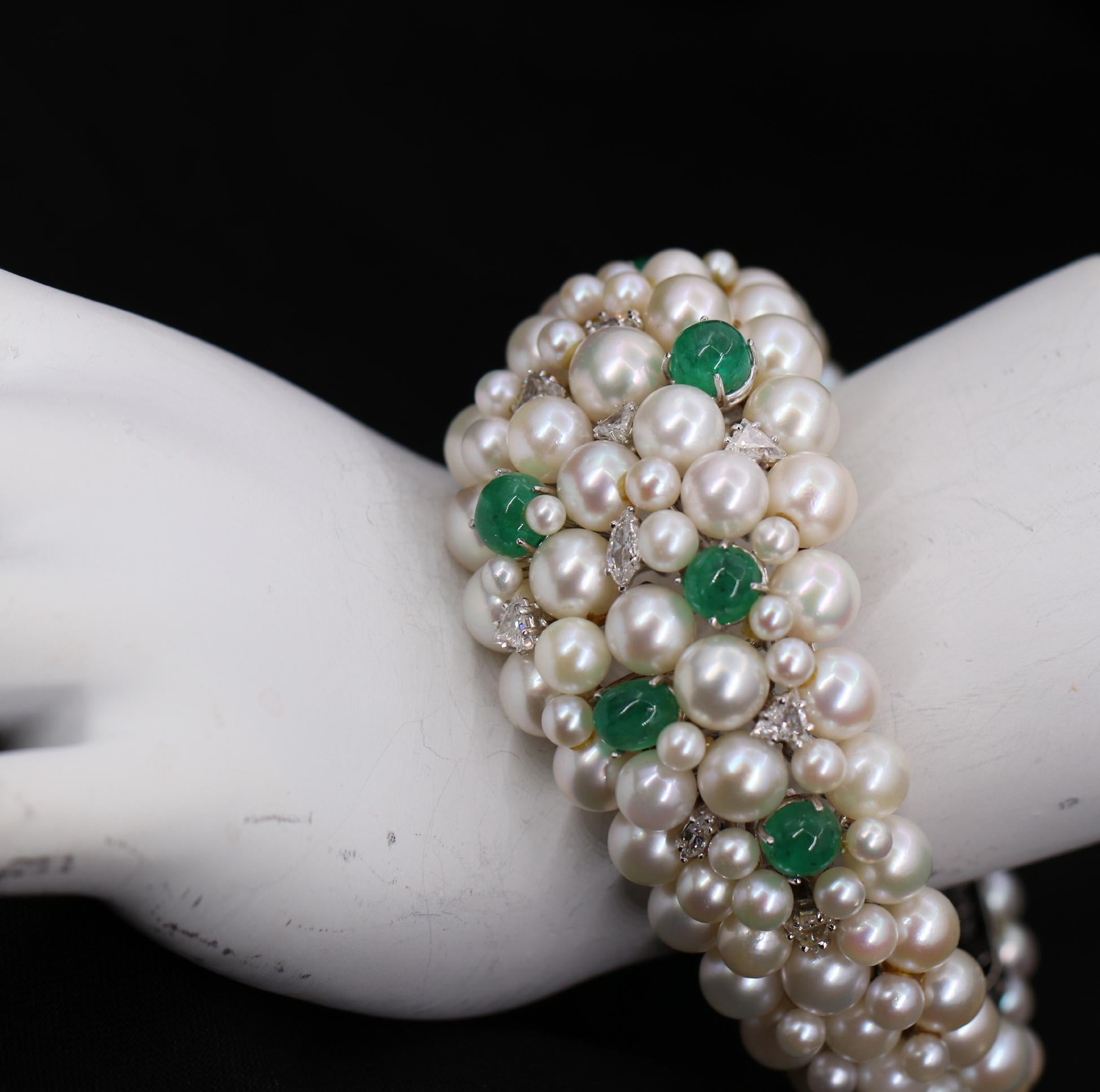 A creative bracelet of bubbly pearls rising above a white gold frame, set with 6 cabochon emeralds, 7 triangular cut diamonds, and 3 marquise cut diamonds. The emeralds weigh a total of approximately 1.75ct, and are an evenly balanced green color.