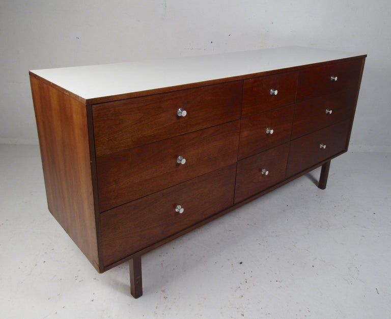 A stunning vintage modern nine-drawer dresser with a white laminate top and sculpted pulls. This stylish case piece offers plenty of room for storage within its many drawers. Please confirm item location (NY or NJ).