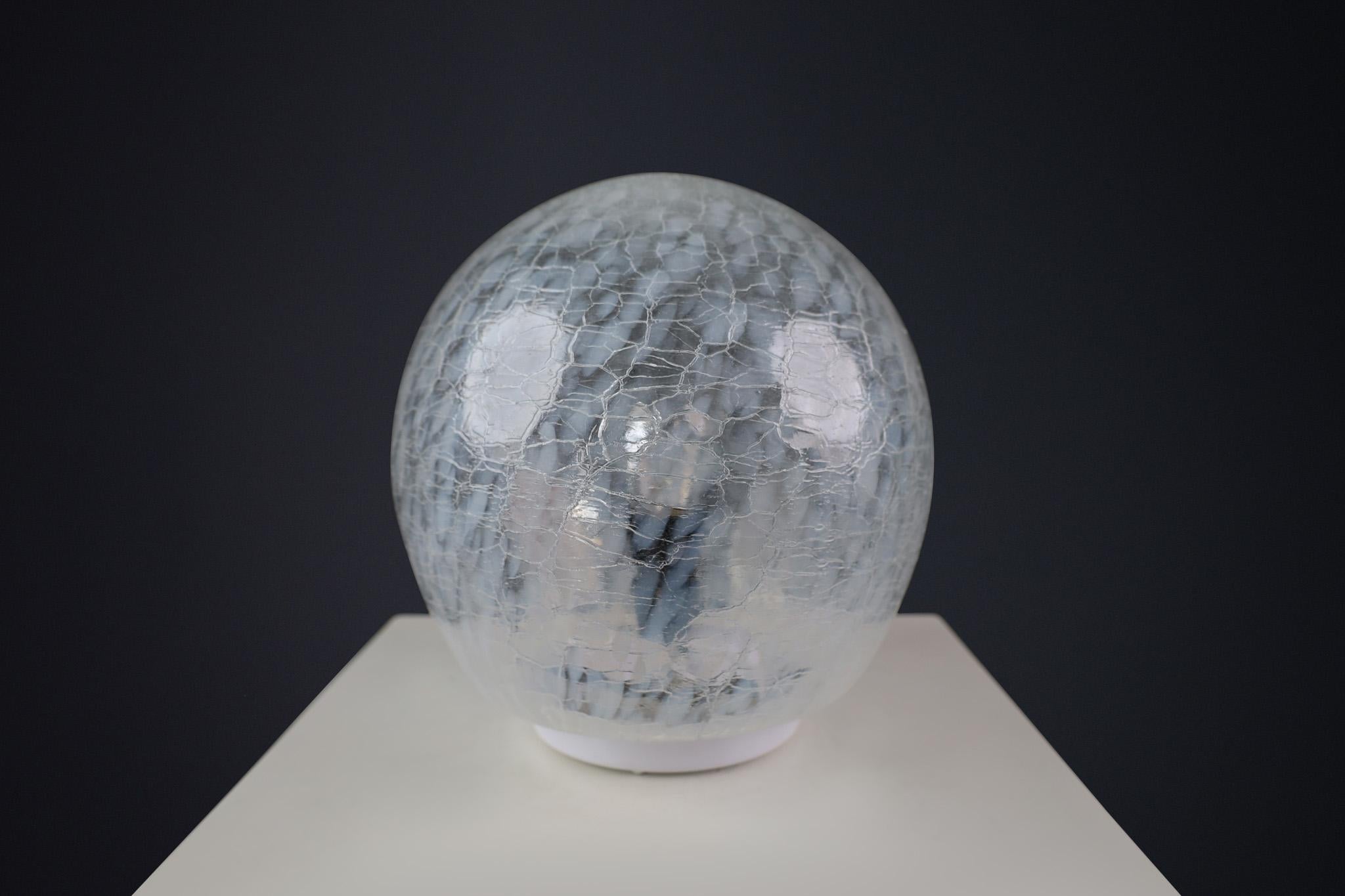 Mid-Century Murano Glass Desk/Table Lamp, Italy 1970s

This 1970s table lamp is crafted from Murano glass in Italy. Its globe-shaped shade and distinct patterns are characteristic of Murano glass from that era. This beautiful piece seamlessly