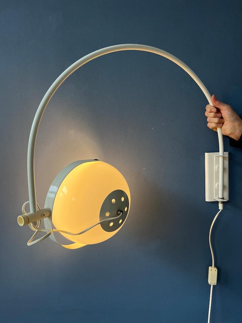 Mid century space age arc wall lamp with white mushroom shade. The acrylic glass shade can be positioned inside and outside the arc. The arc can move left and right from the position of the wall bracket. The lamp requires an E27/26 (standard)