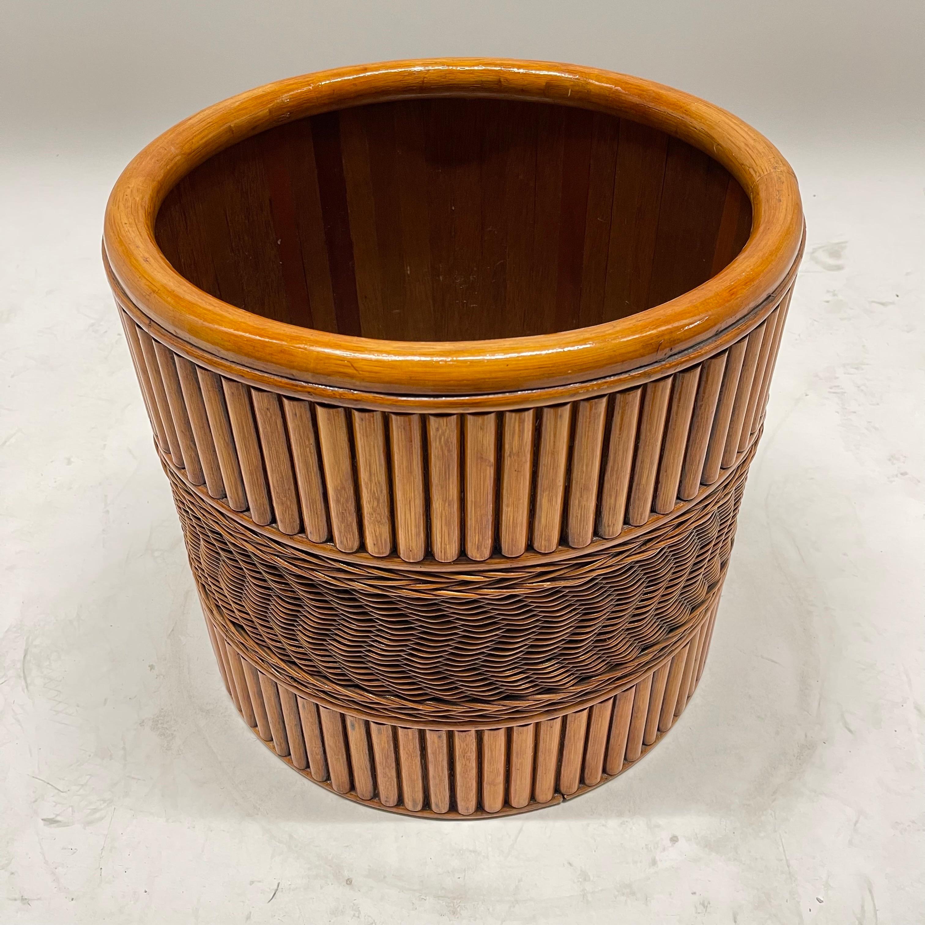 Intricate graphic and geometric midcentury planter or garden pot basket. Rendered in handwoven wicker with a reeded design of rattan slats. USA, circa 1970s.

Interior dimensions:
16