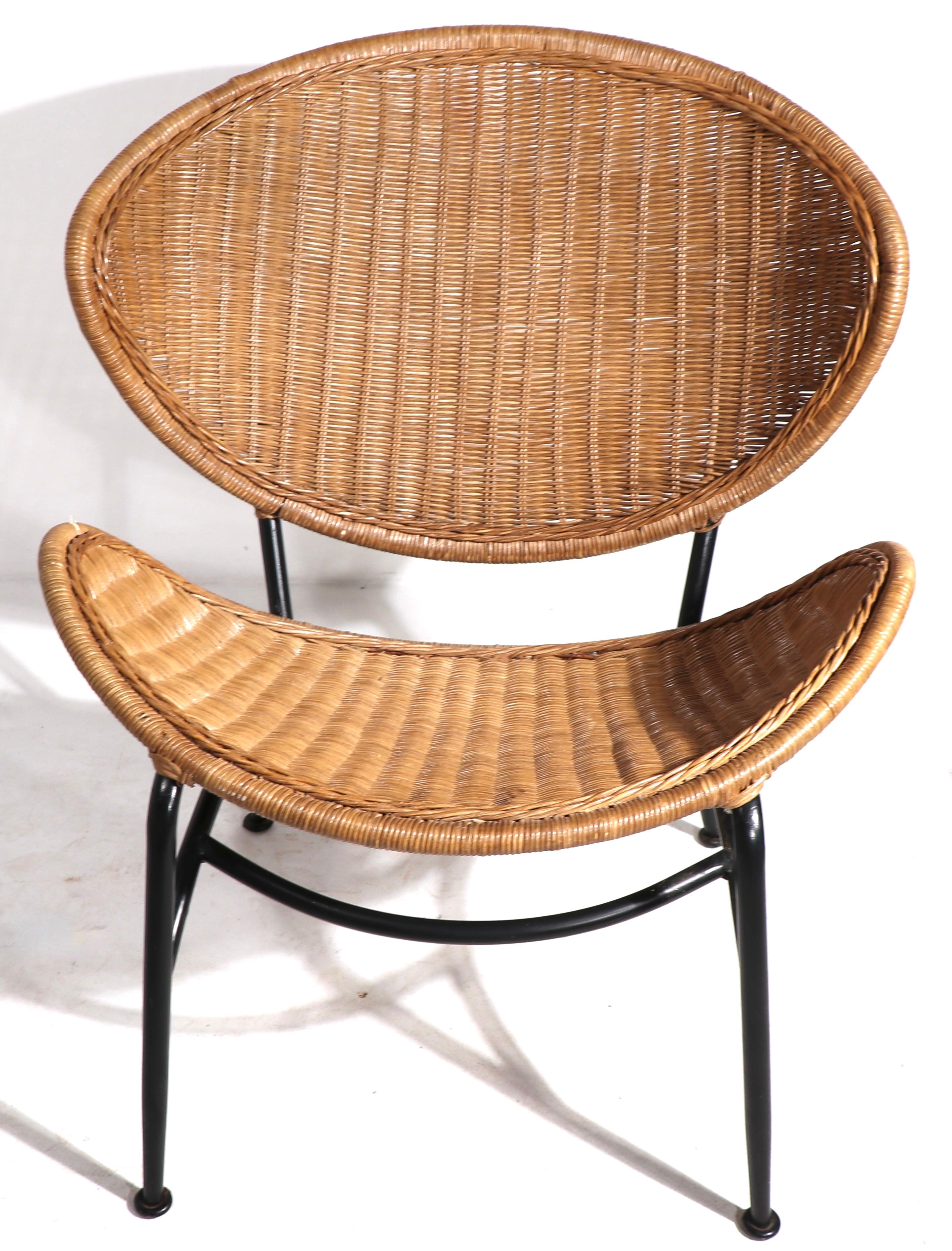 Chic and stylish mid century wicker and metal lounge chair, in very good original condition. The chair features an exaggerated oval back rest, tubular metal frame in original black paint finish- and wide wicker seat. Vintage 1950’s chair, clean,