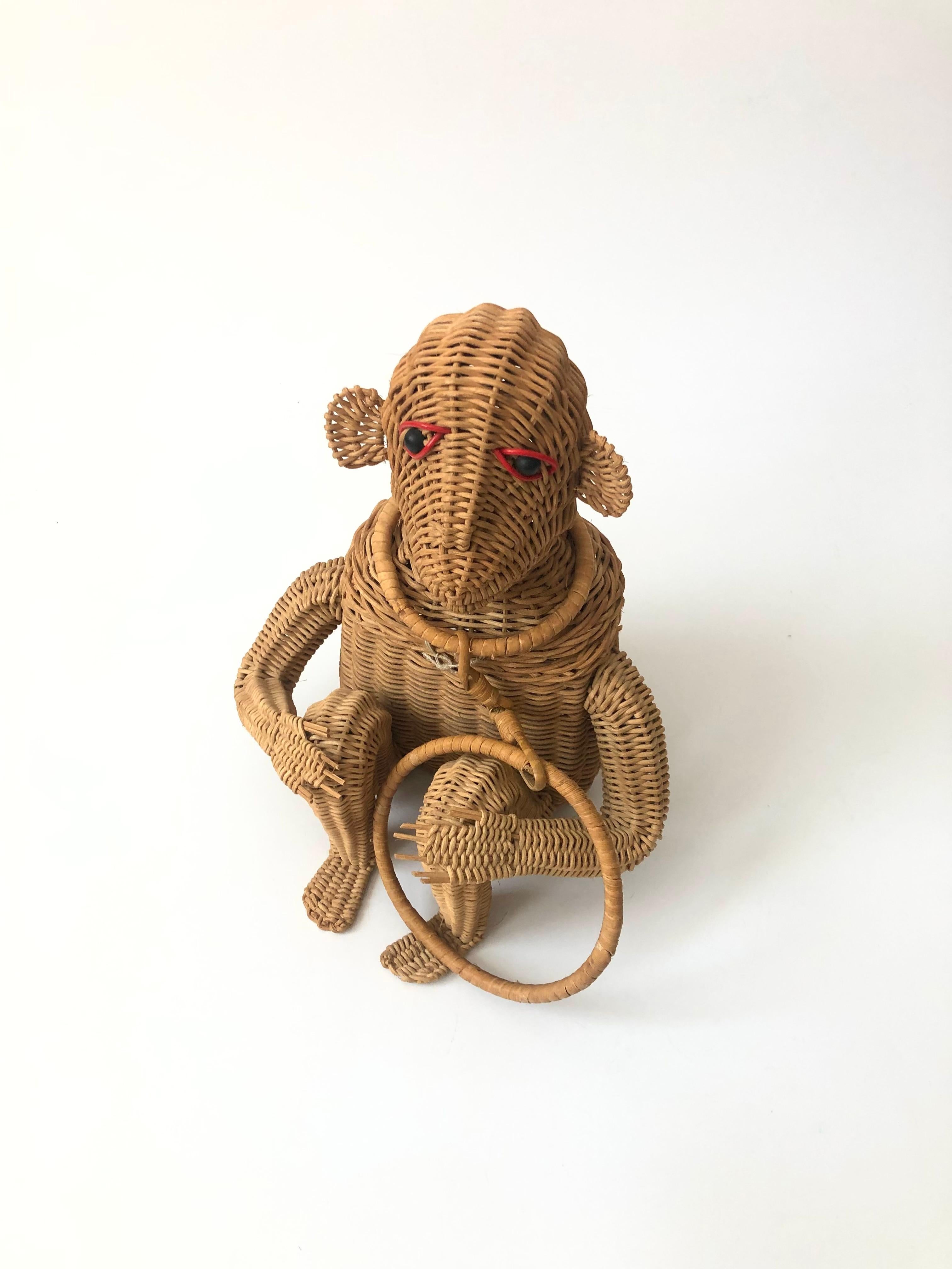 A mid century figural wicker purse in the shape of a monkey. An adorable design of a seated monkey made with great attention to detail to create the monkey's features. Red plastic line the eyes. Hinges open from the front to reveal a roomy interior.