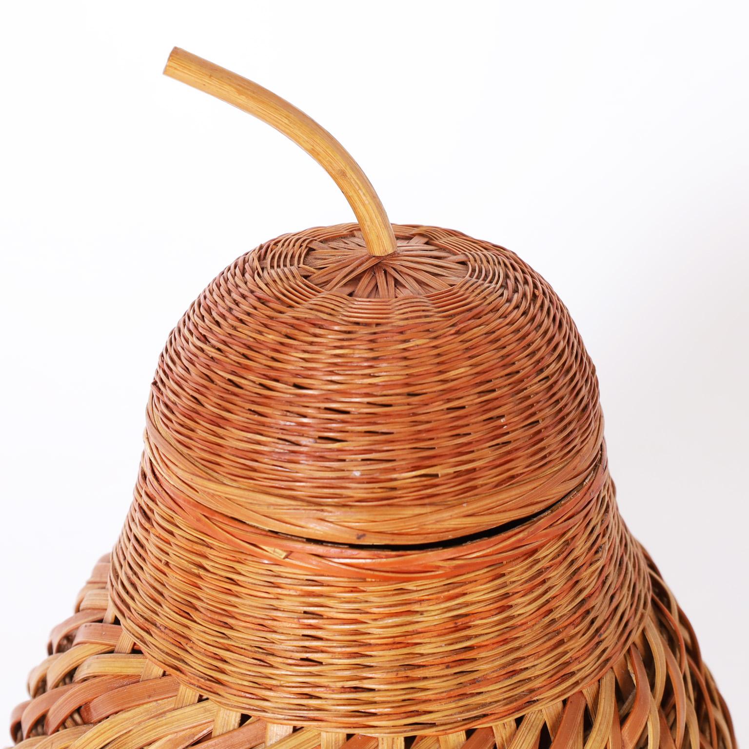 Shapely pear form lidded container ambitiously crafted with woven reed in several patterns over a ceramic vessel.