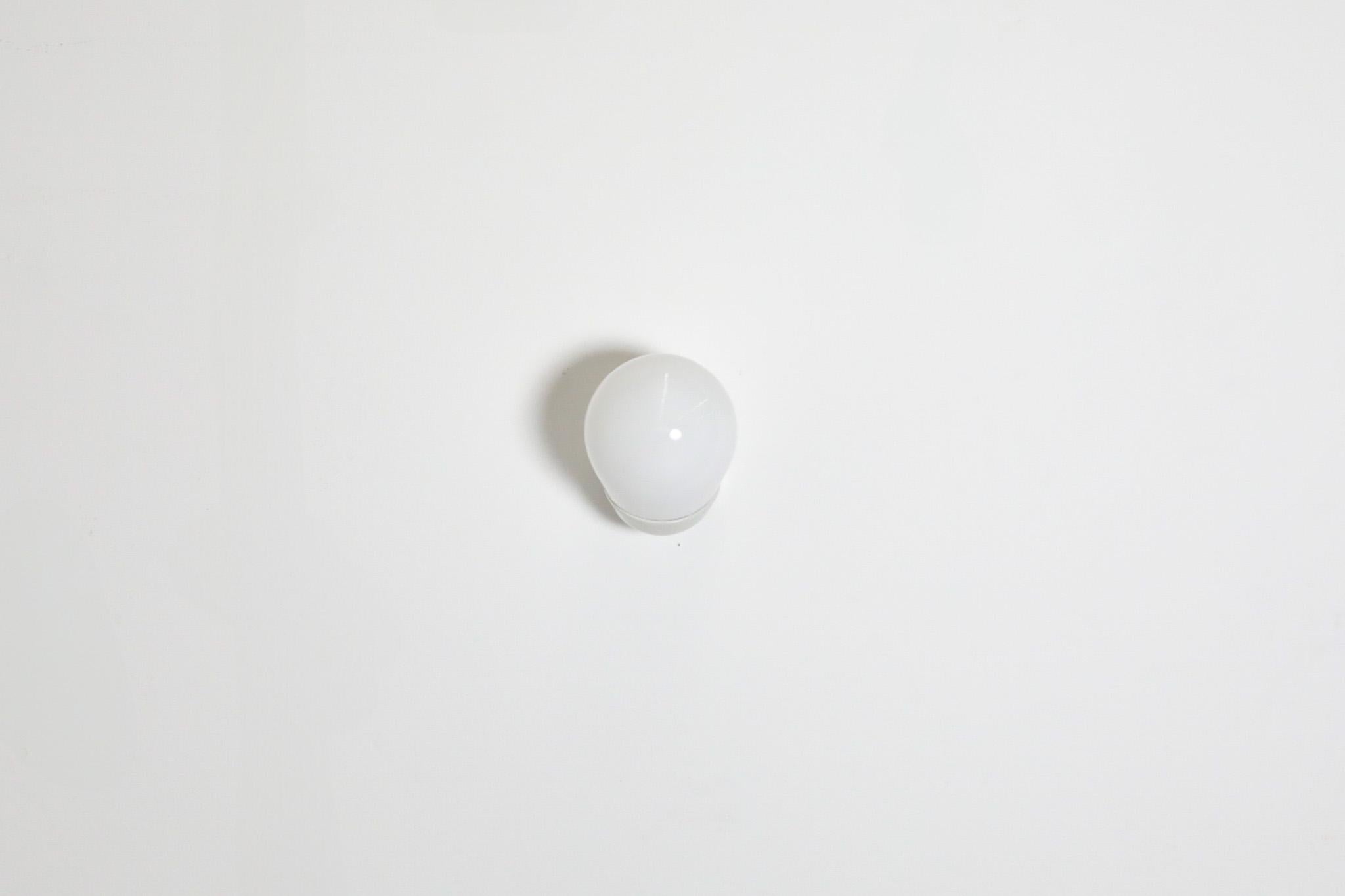Aplique de pared o techo muy buscado, obra de Wilhelm Wagenfeld para Lindner Alemania. Este diseño minimalista tiene una base angular de porcelana vitrificada y una pantalla de cristal opalino. En estado original con desgaste visible, incluida una
