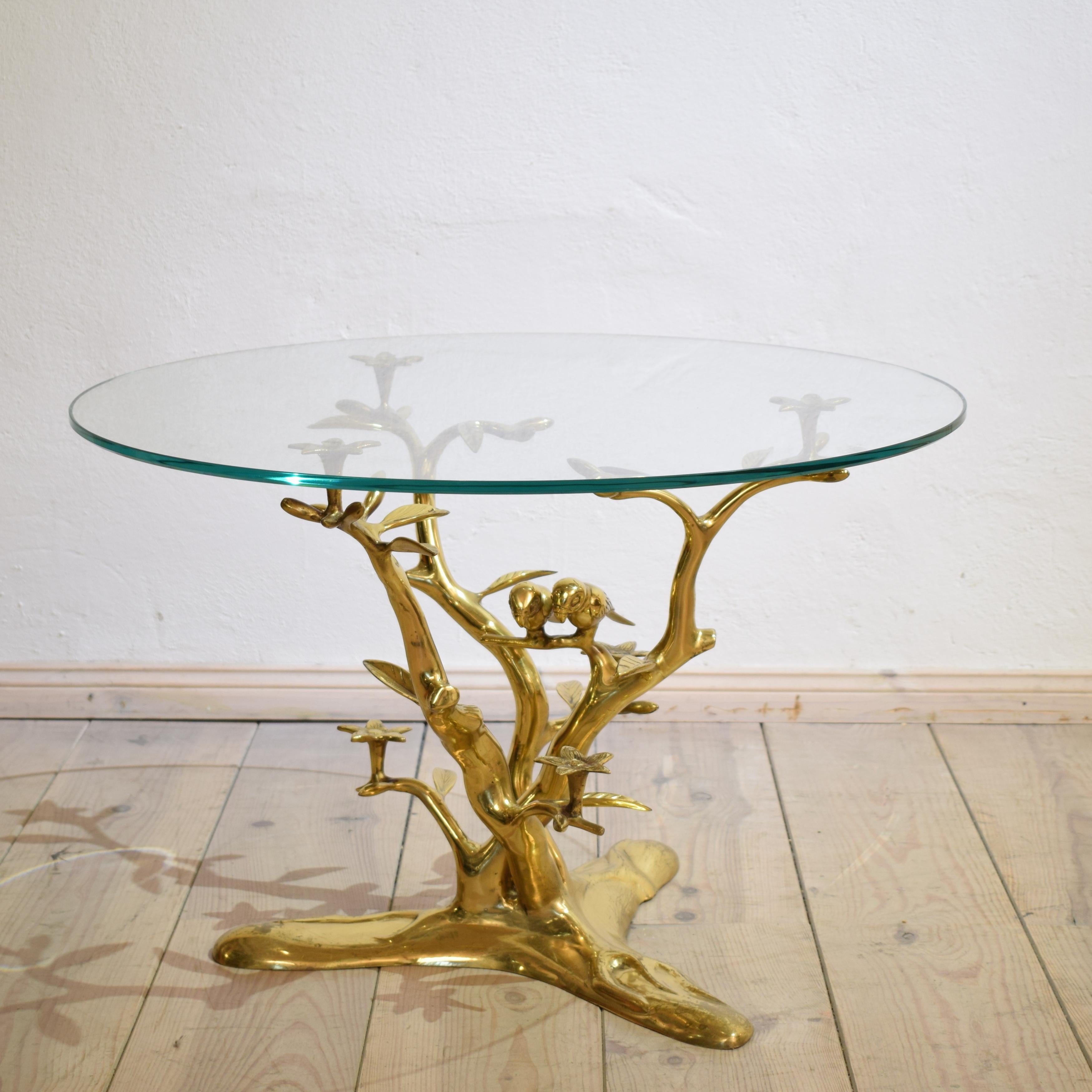 This coffee table by Willy Daro with the organic tree form with flowers and pair birds. Table base has a circular glass top. The table features a sculptural brass base with branches and leaves. The table is a great piece, and is pretty to look at
