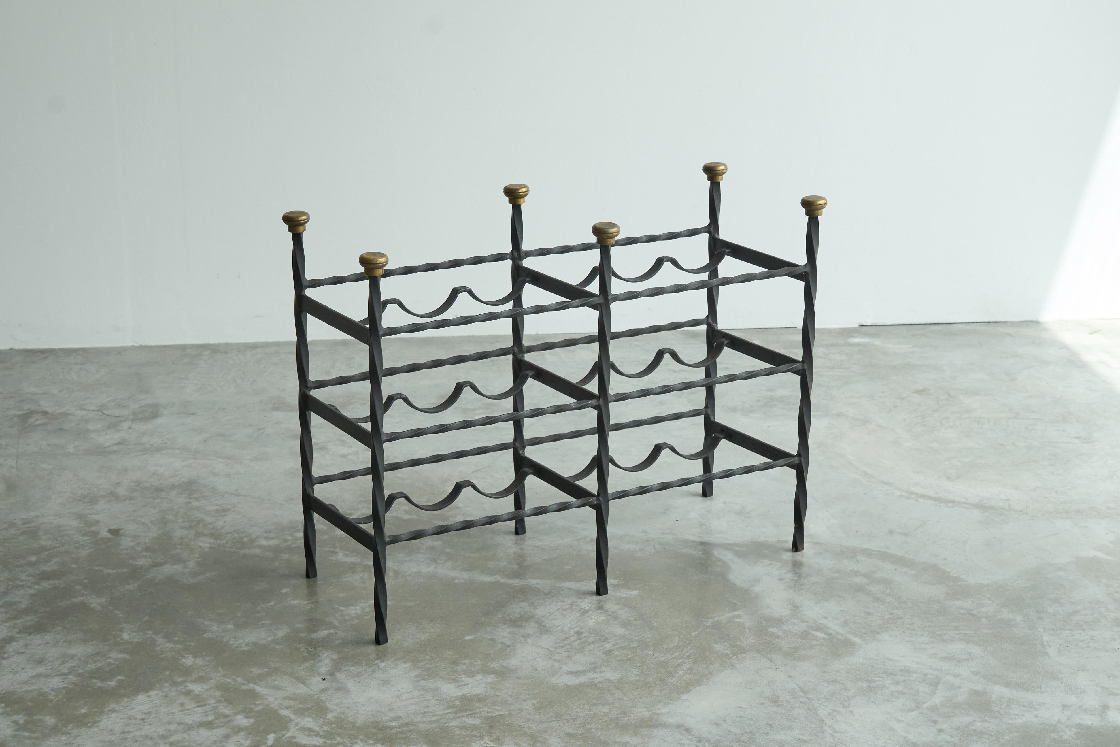 Mid Century Wine Rack in Wrought Iron Brass, Europe, 1960s.

This is a great mid century wine rack in wrought iron with nice brass details. Hand wrought iron with a very nice artisanal quality. The spiraling pillars and the brass finials make for a