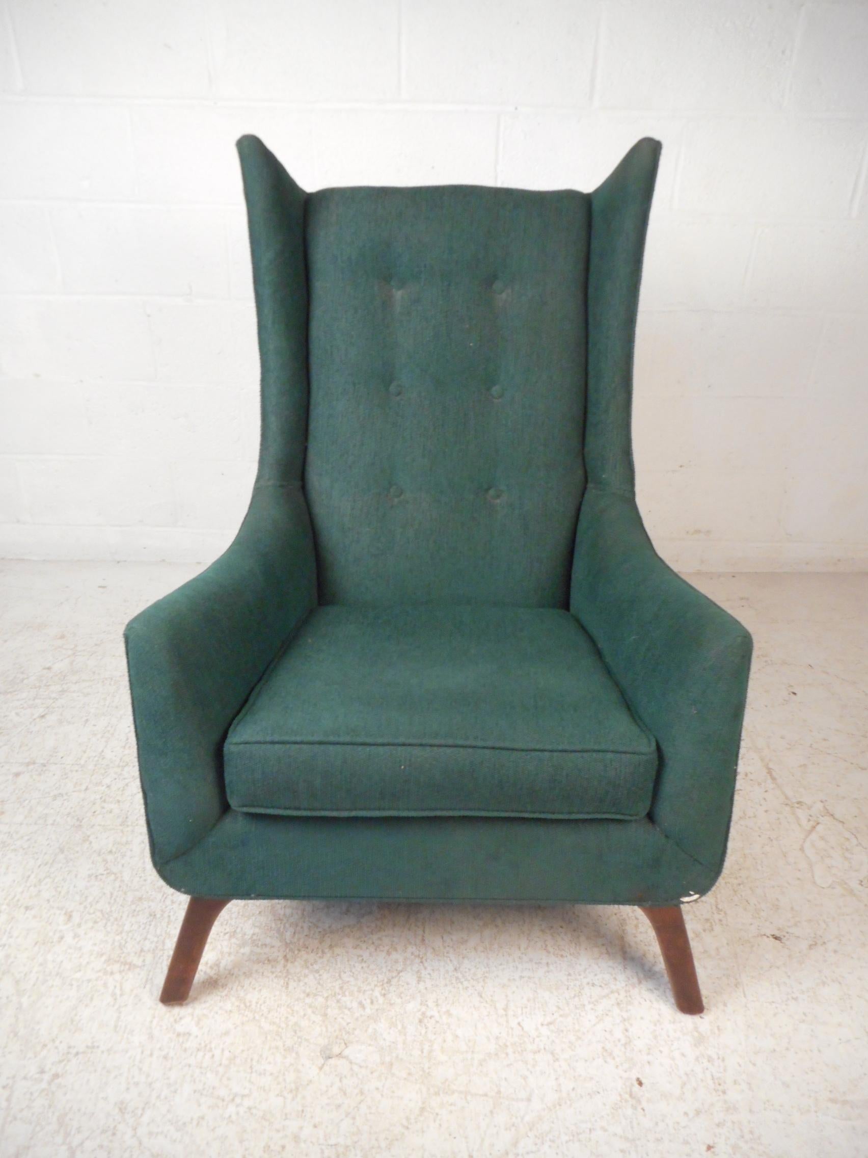 Impressive midcentury wingback chair. Tall backrest with accented sides giving this piece a striking visual profile. Vintage green upholstery with tufted backrest. Great addition to any modern interior's seating arrangement. Please confirm item