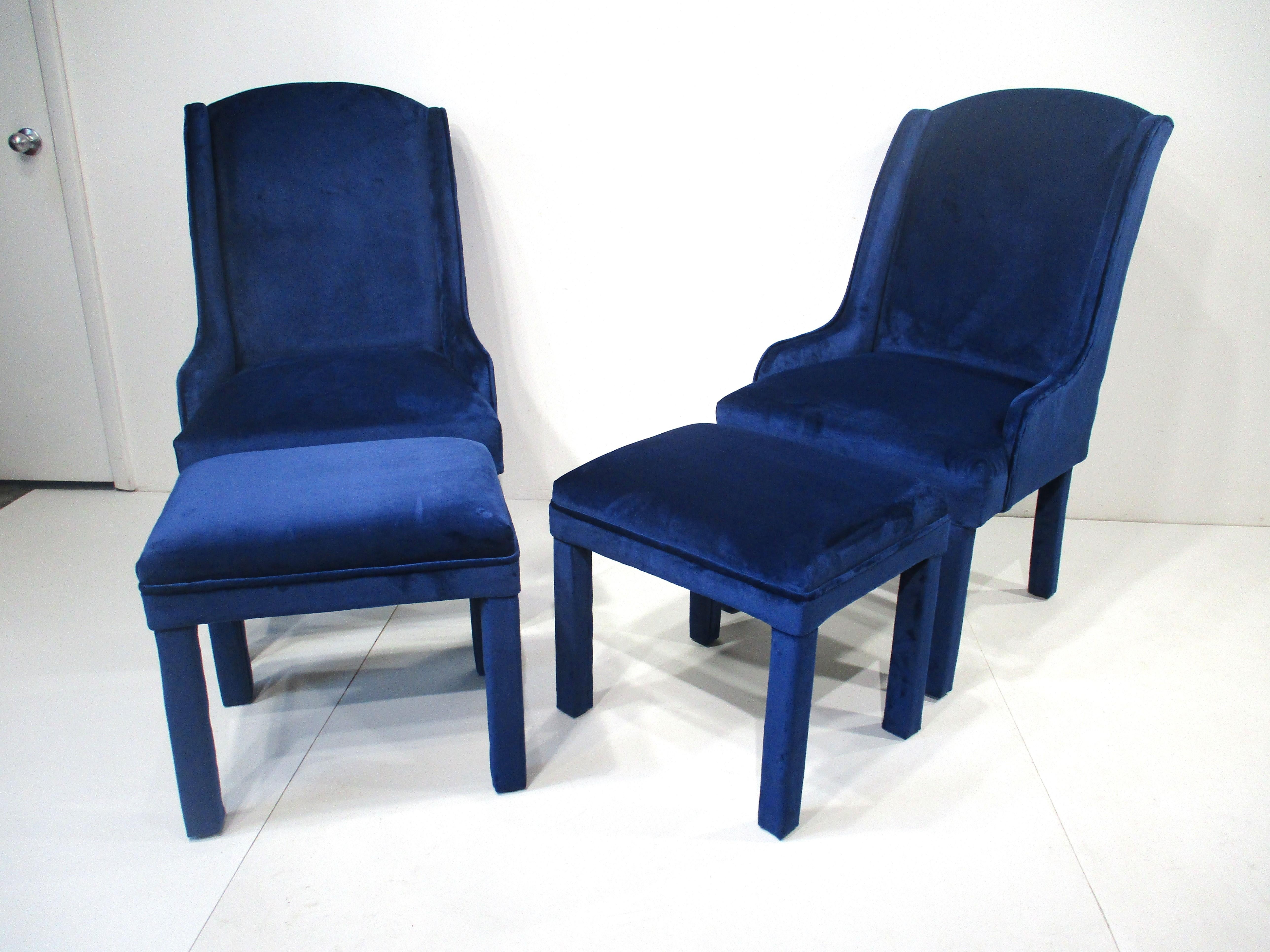 A pair of deep ocean blue smooth velvet Mid Century styled wing back lounge chairs with two matching ottomans . The chairs have higher backs and the sitting position is very comfortable , also included are two pillows in the same fabric . Designed
