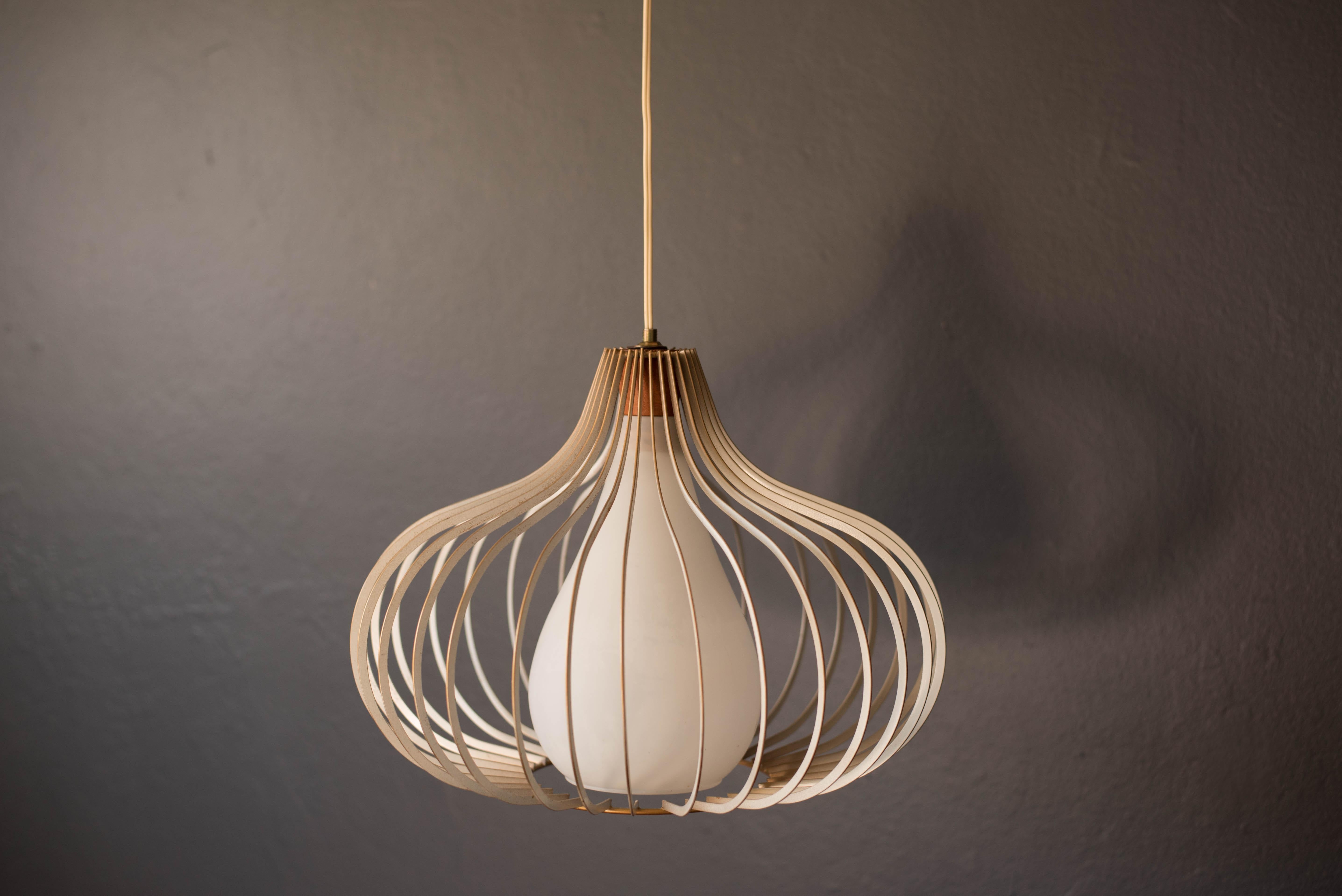 Vintage hanging wire pendant lamp circa 1960s. This piece has a frosted white teardrop glass pendant and walnut stem surrounded in a contoured metal frame.
