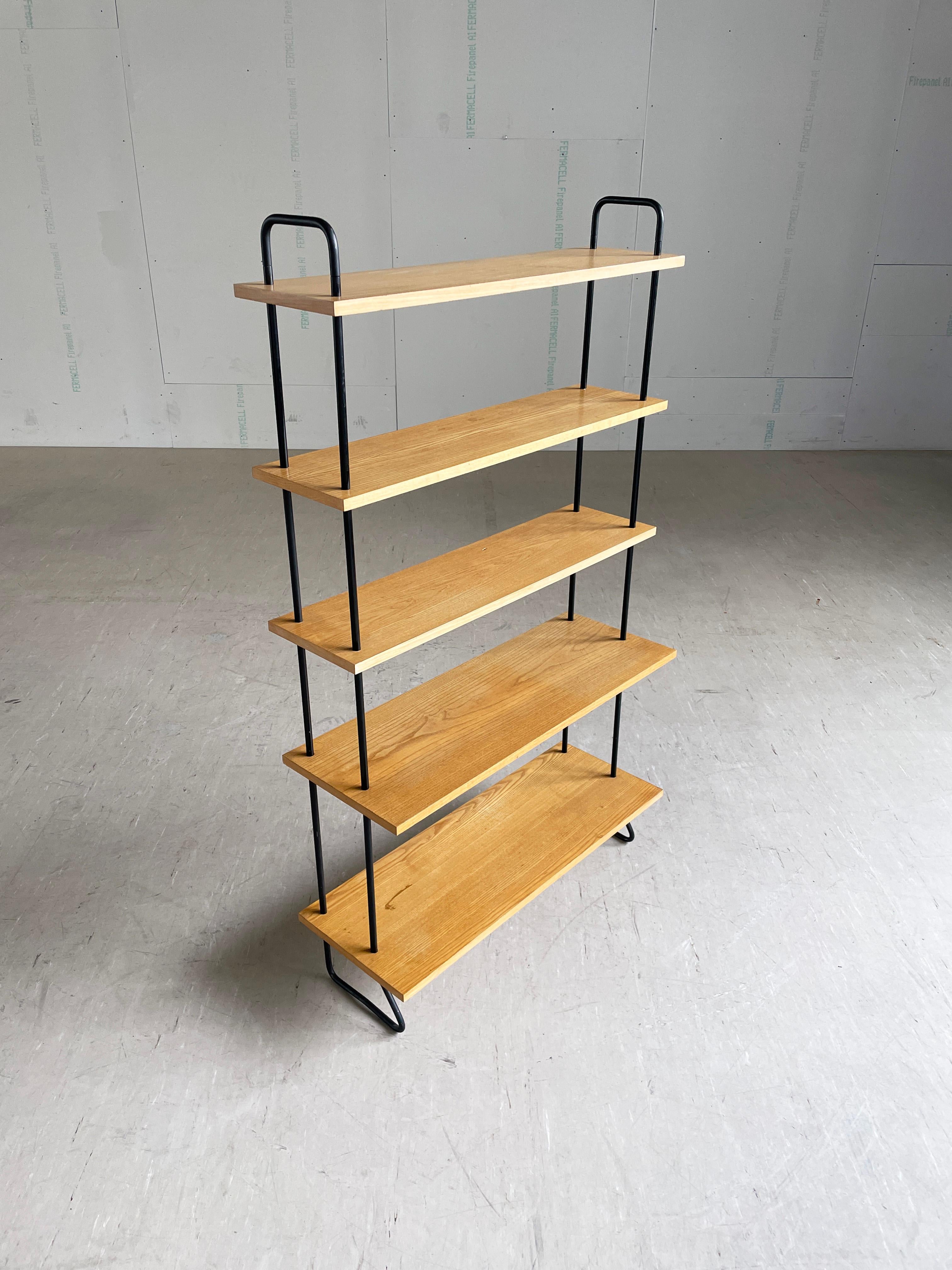 Sistema di scaffalature modulari di metà secolo. Costruito con elementi tubolari in acciaio e ripiani impiallacciati in legno di faggio. Il ripiano più basso misura 30,5 cm di profondità. I ripiani rimanenti misurano 20,5 cm.
È molto facile e veloce