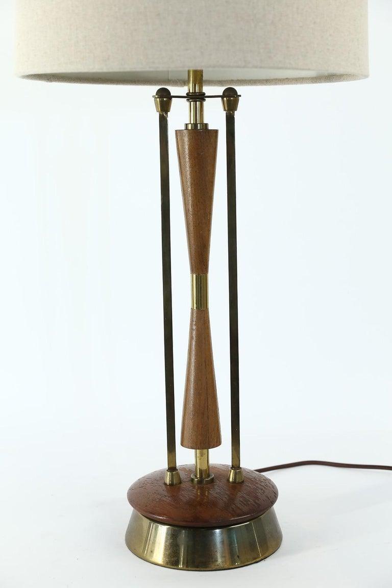 This mid-century wood and brass table lamp has been newly wired to meet United States standards. The lamp has a beautiful organic look. The new shade is included and dimensions are: 14
