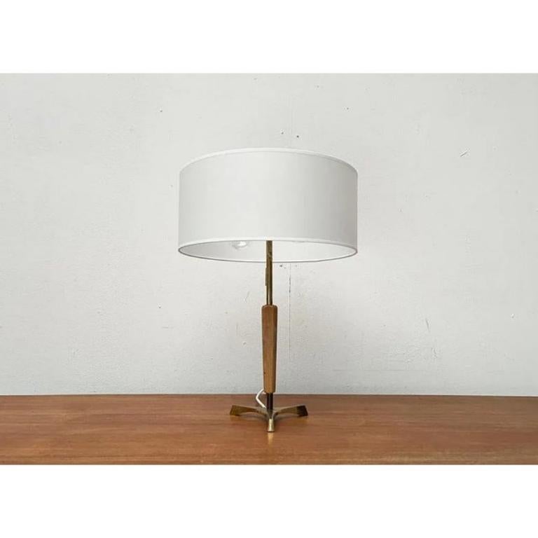 Rara lámpara de mesa trípode de mediados de siglo.

Un diseño elegante de especial materialidad. El latón está encerrado en la zona inferior con una madera. El eje se encuentra arriba y abajo. Un detalle llamativo es el elaborado pie de trípode de